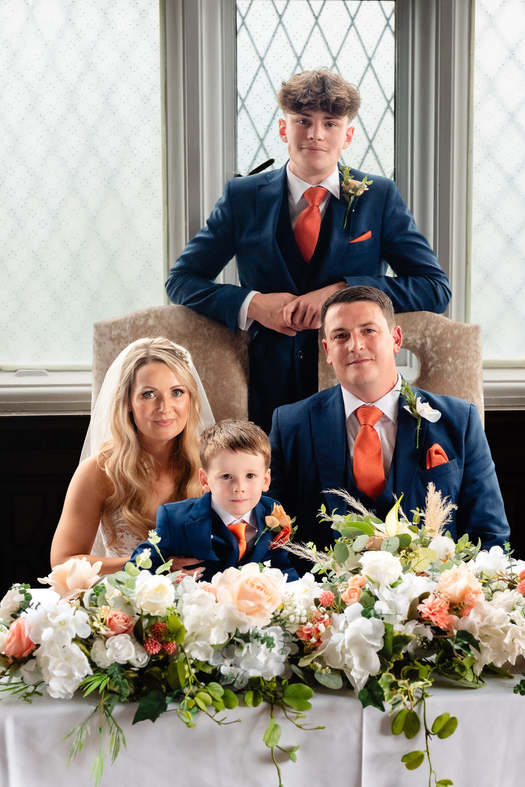 Lauren, Dan, Zach and Alexander together at the signing table, banked cream and peach flowers across the front