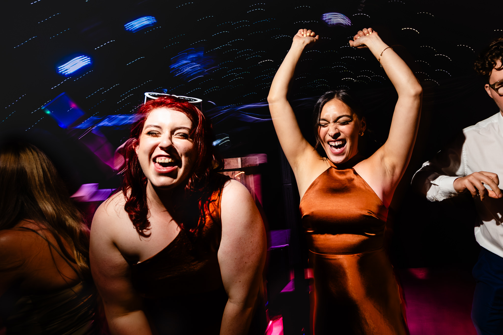 Two guests dancing with arms in the air surrounded by colourful light trails, Heaton House Farm evening reception