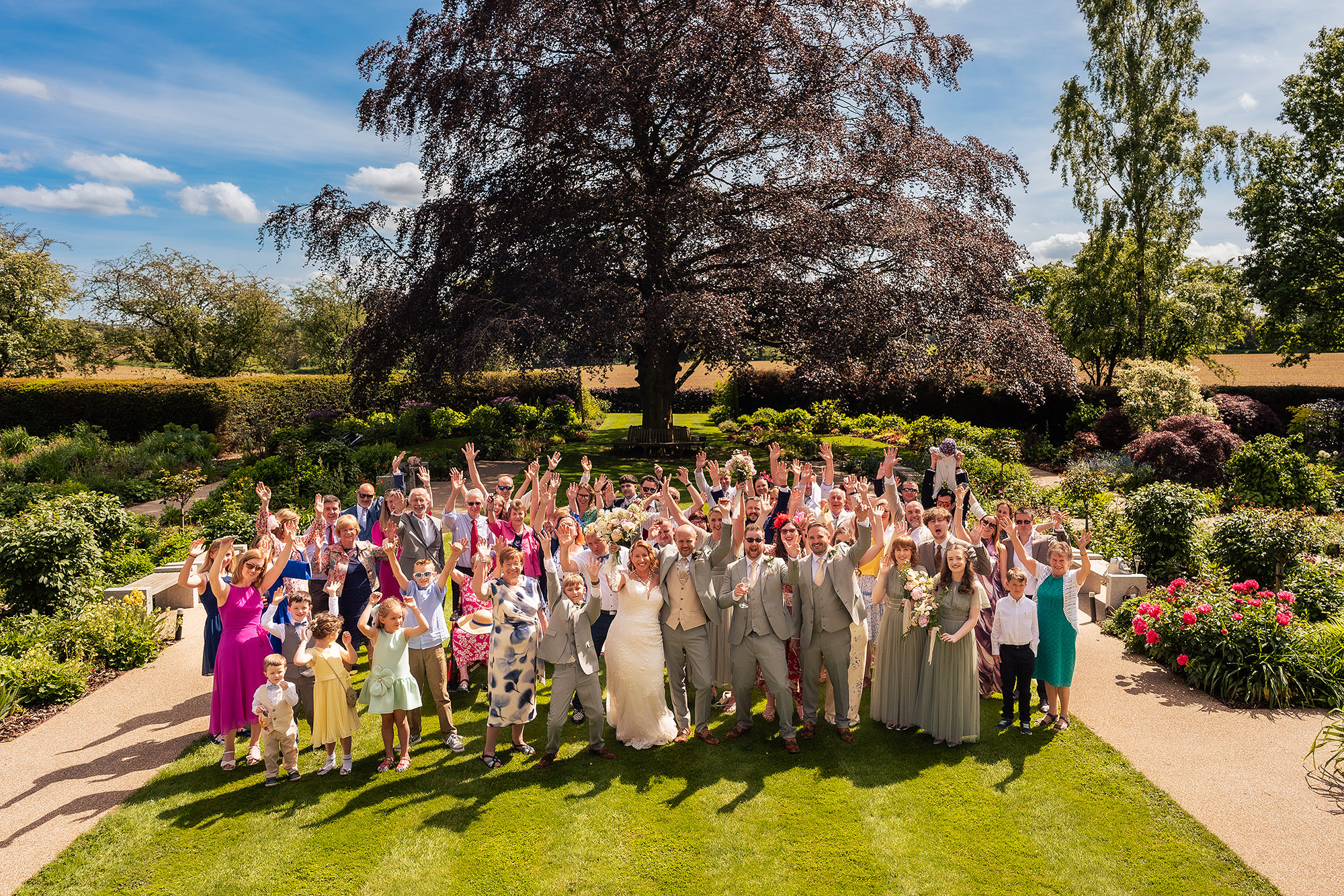 Wedding guests cheering with arms raised during the group photographs at Salt House