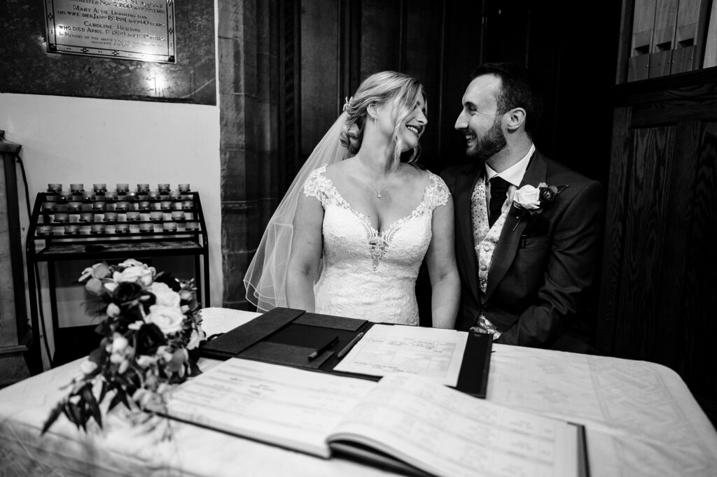 Bride and groom laughing together as they sign the register, black and white, Merrydale Manor wedding photographer