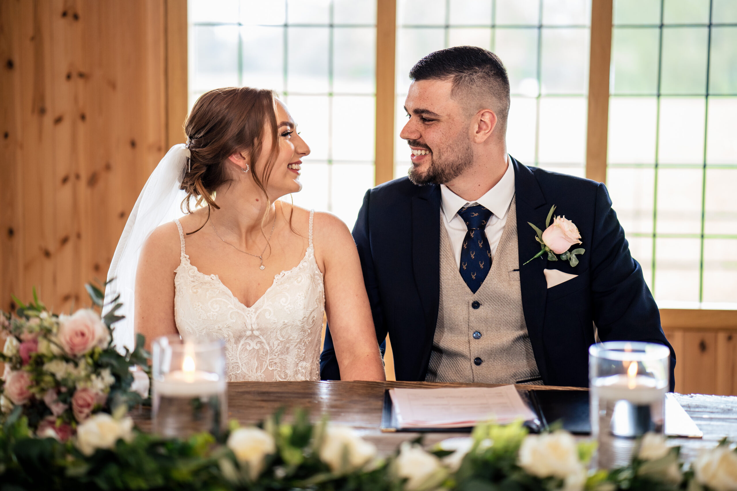 Bethany and Dean smiling at each other while signing the register