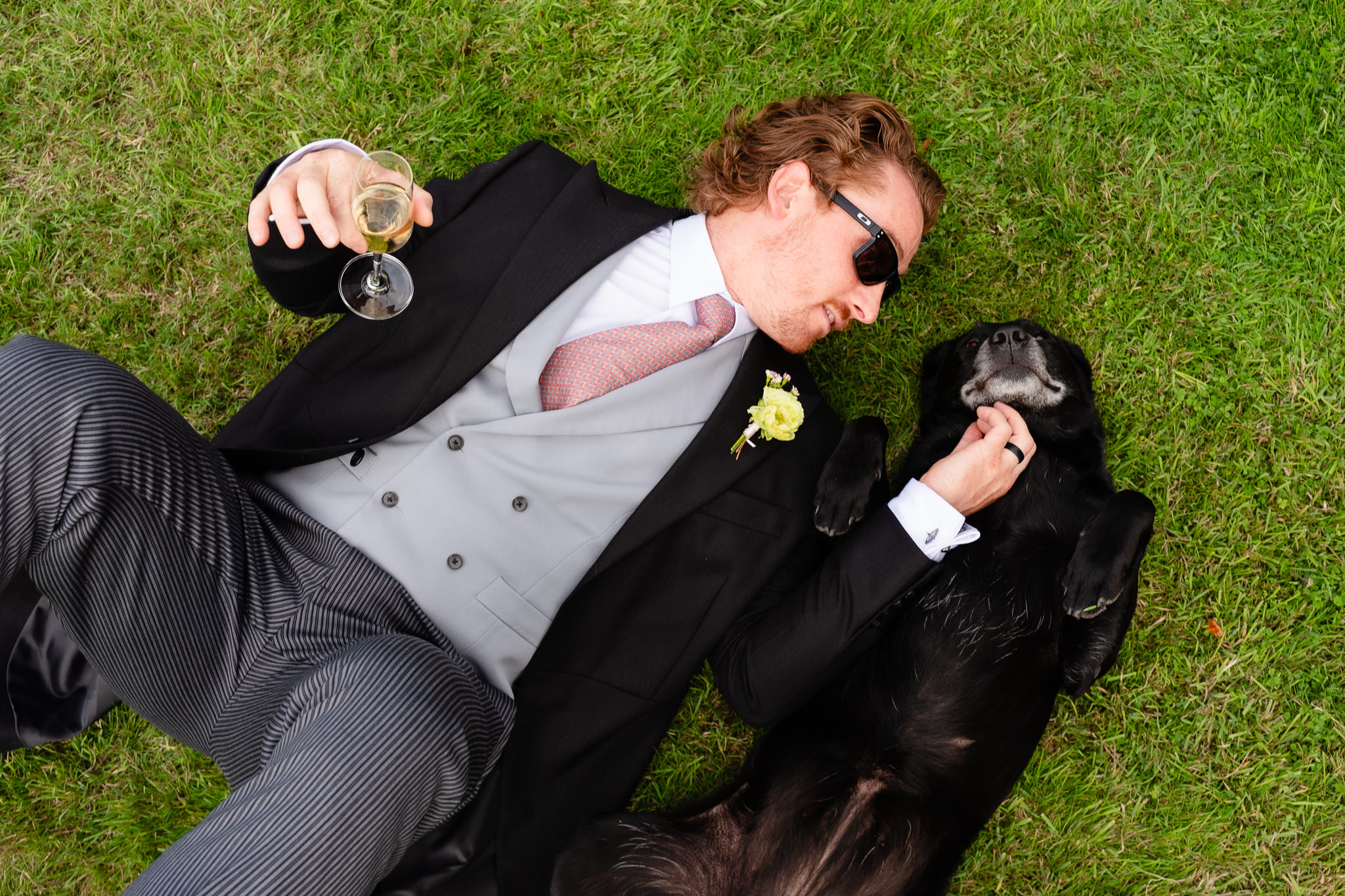 Guest lying on the lawn with Blossom the labrador and a glass of fizz