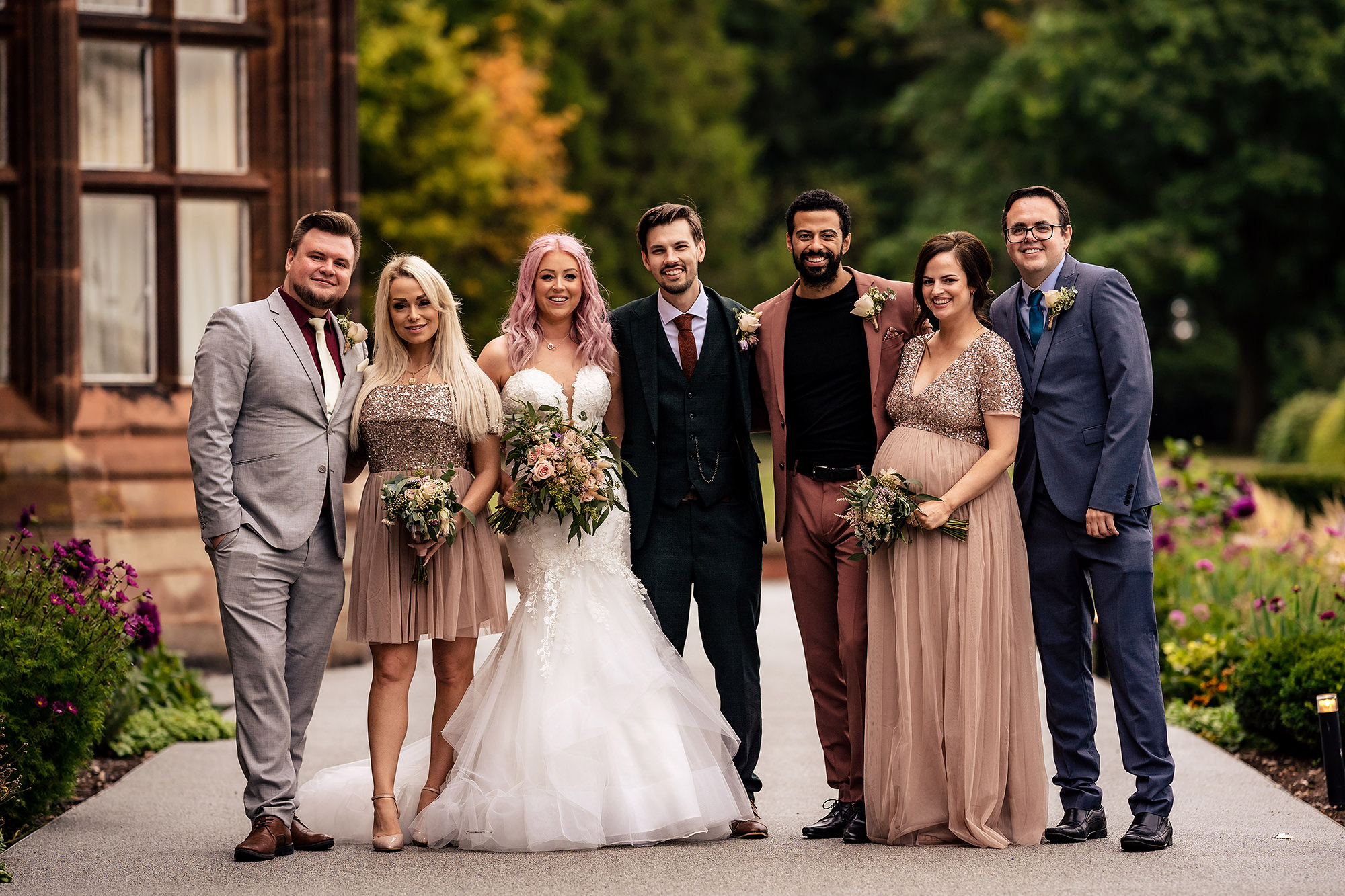 Bride and groom with their bridal party in mismatched autumn colours at Standon Hall