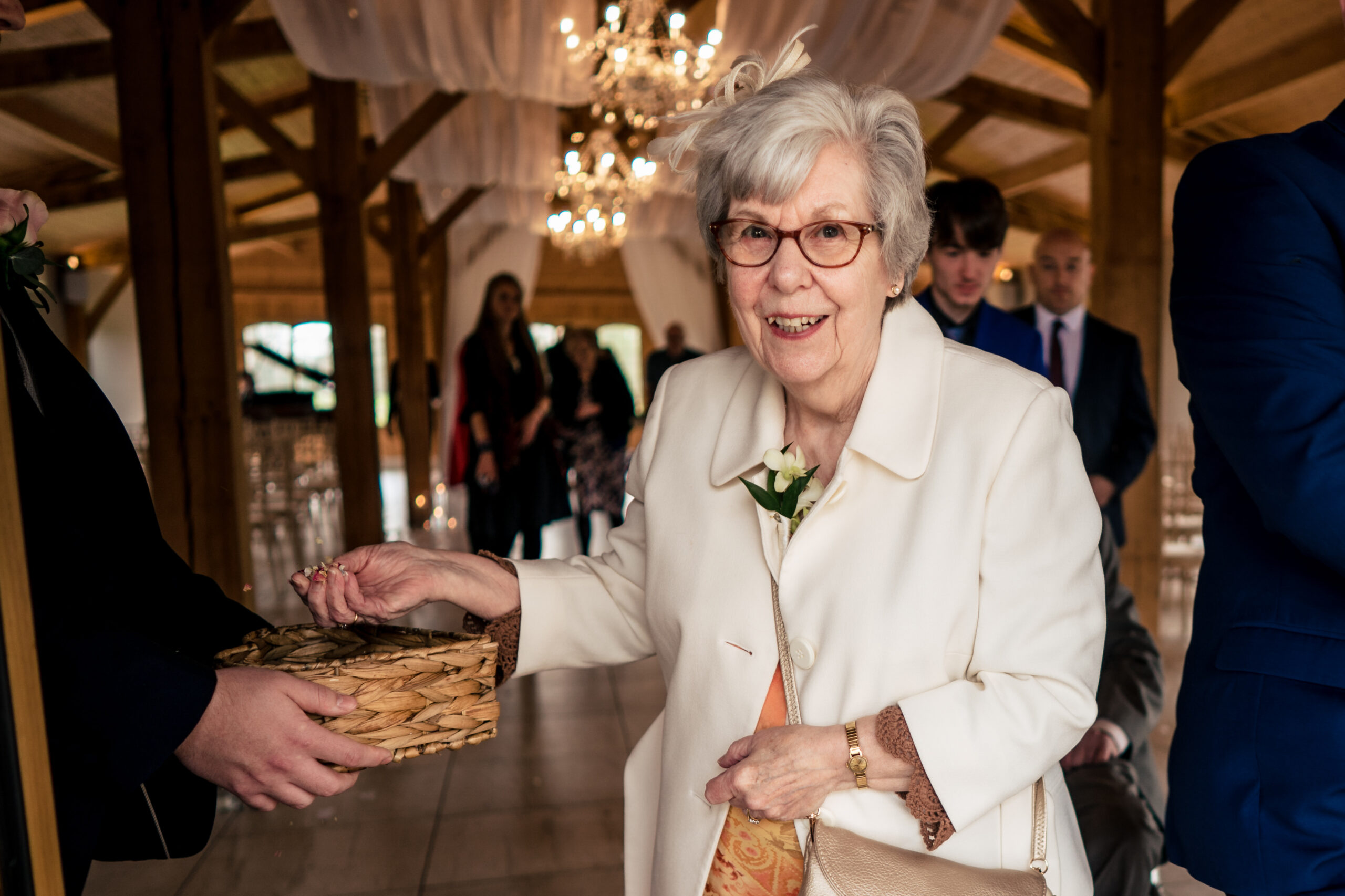 A guest laughing as she grabs a handful of petals from a wicker basket on the way out