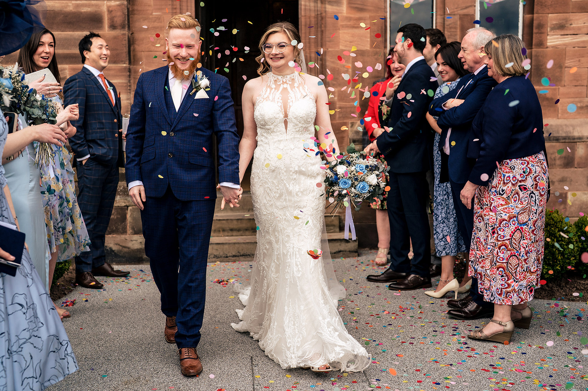 Patrick and Laurel walking through a shower of confetti outside Salt House, Staffordshire wedding photographer