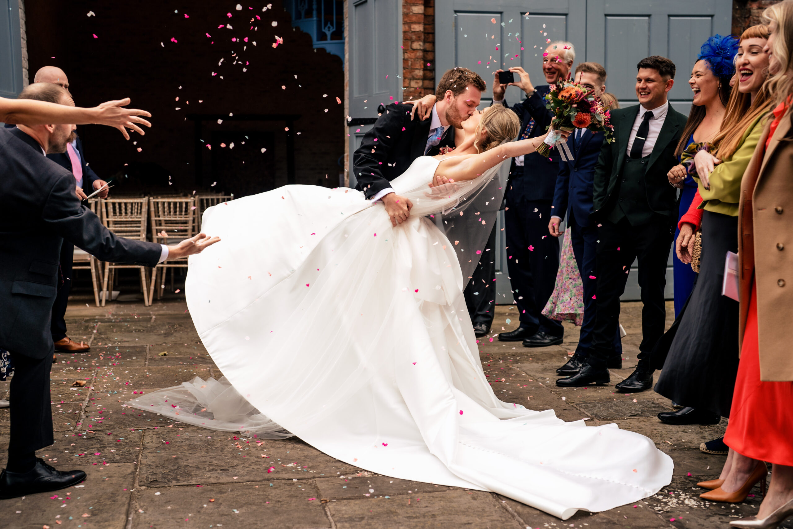 Bride swinging the train of her dress through a shower of petal confetti, Dorfold Hall wedding photographer