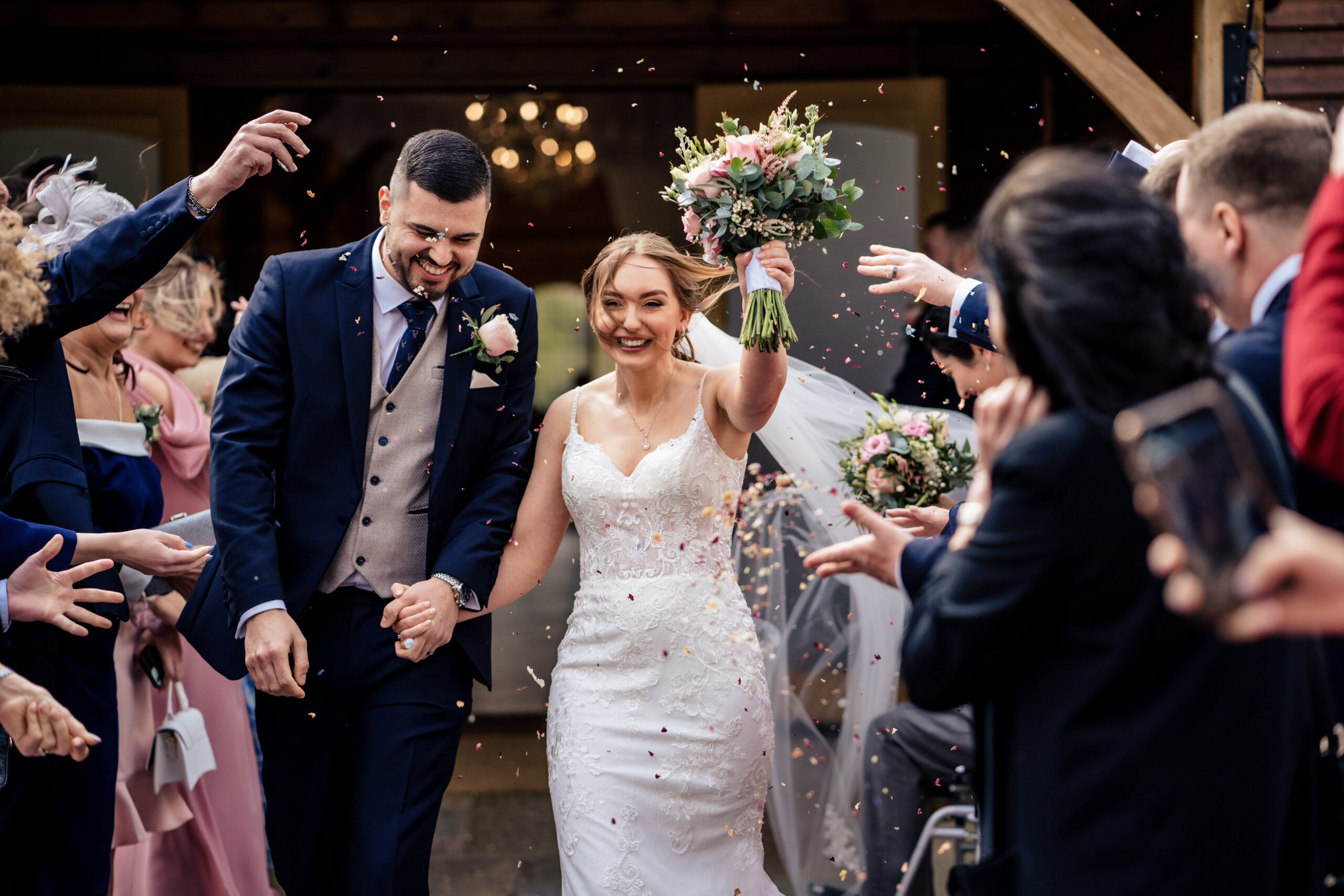 Dean and Bethany walking through a shower of petal confetti outside the Ceremony Room at Merrydale Manor