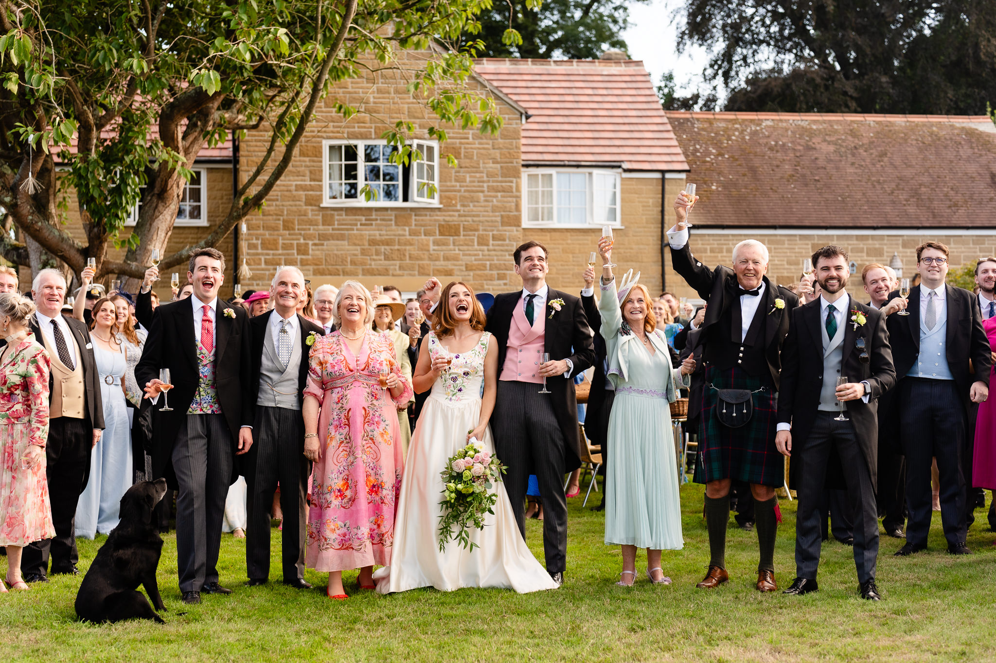 Wedding party throwing their arms in the air during the big group photograph, Dorset marquee wedding photographer