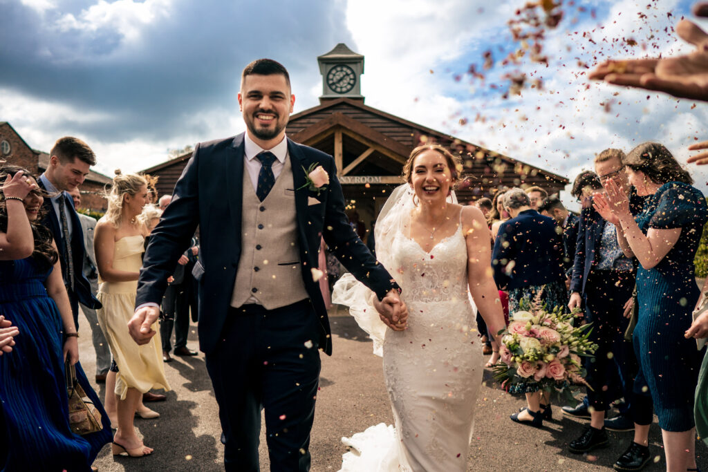Confetti flying over Dean and Bethany with the Merrydale Manor clock tower behind them