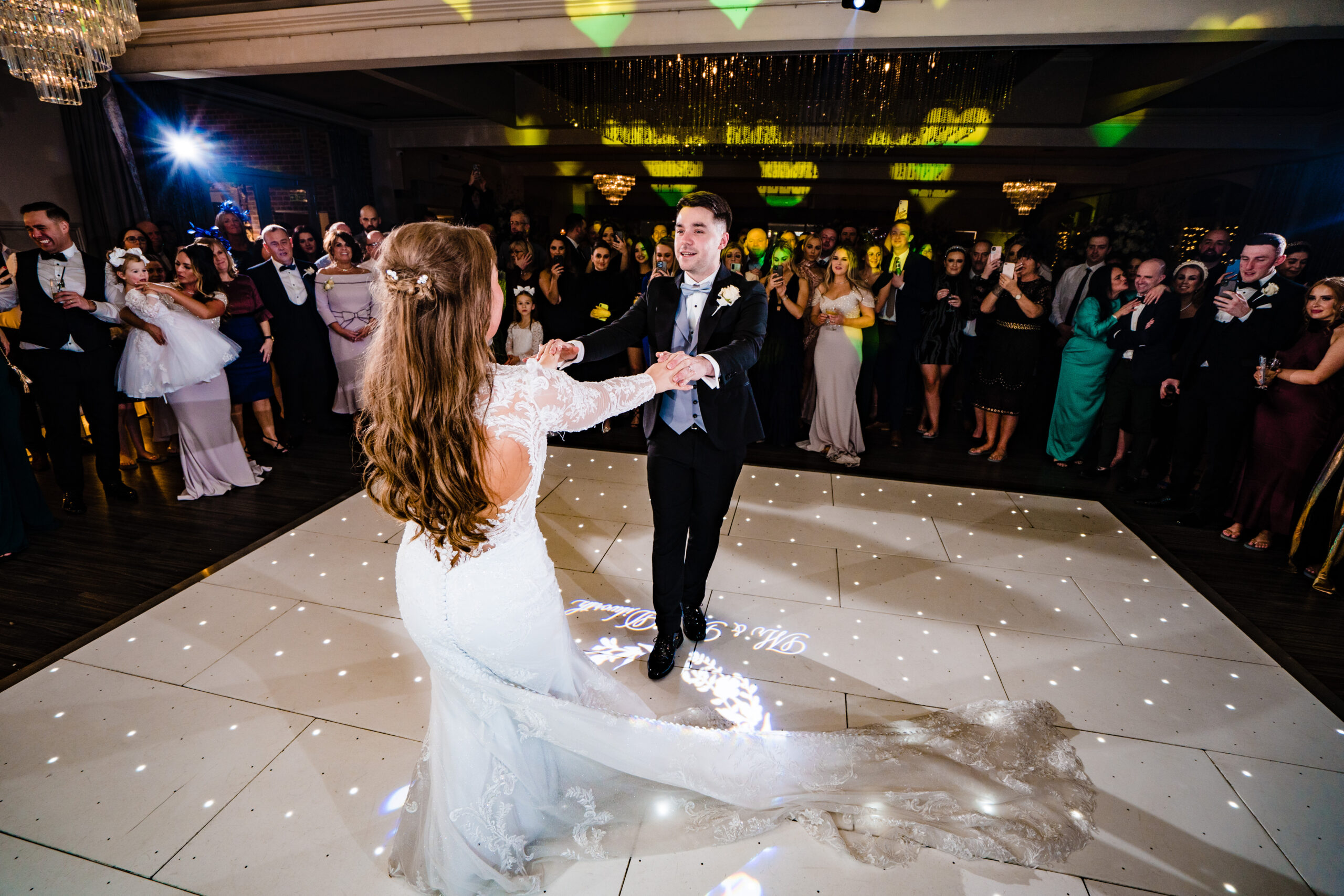 Abbie and Jamie’s first dance on the starlit dance floor with guests gathered round at Merrydale Manor