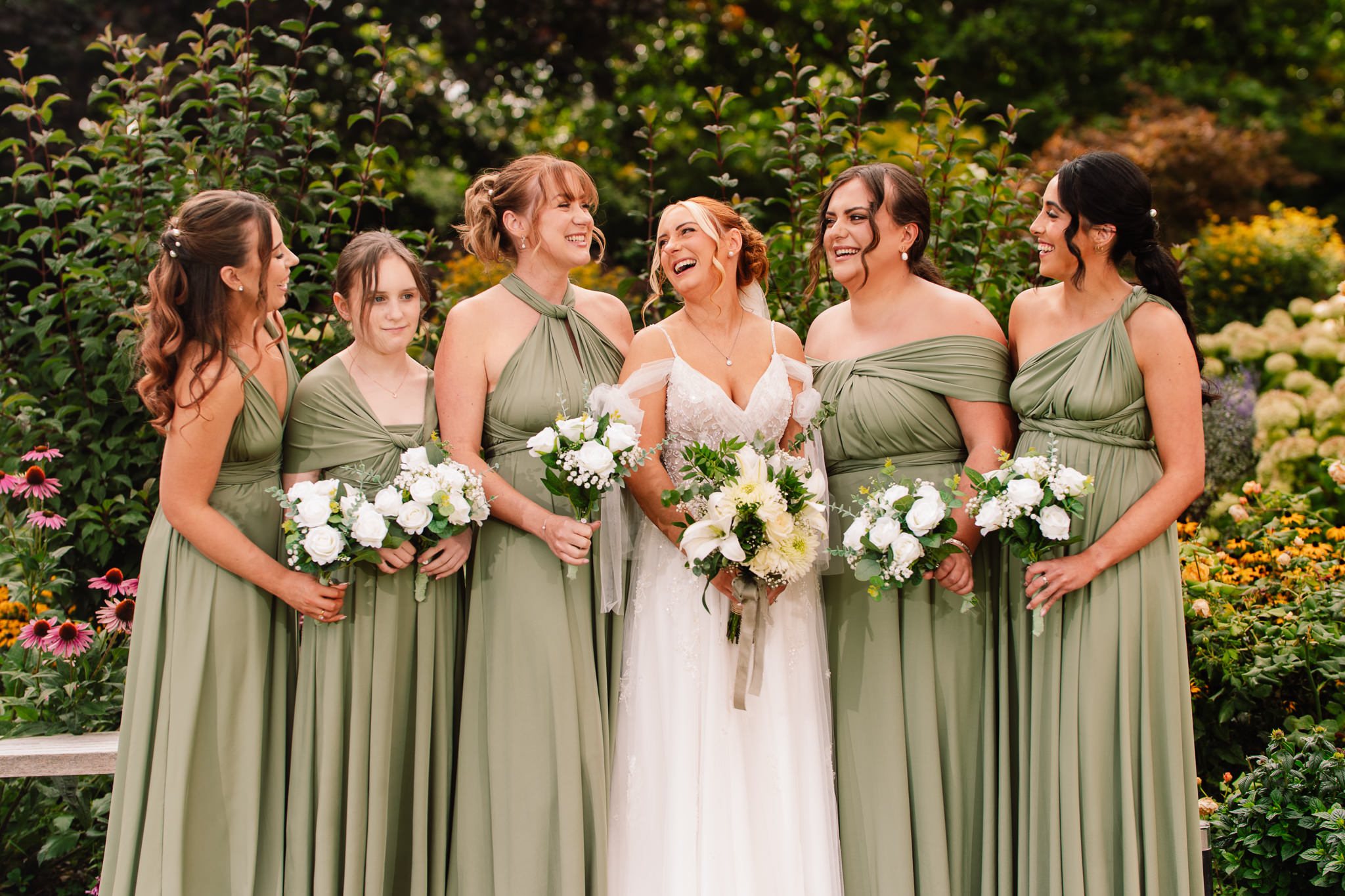 The bride and groom walking through the gardens with the whole bridal party, everyone laughing