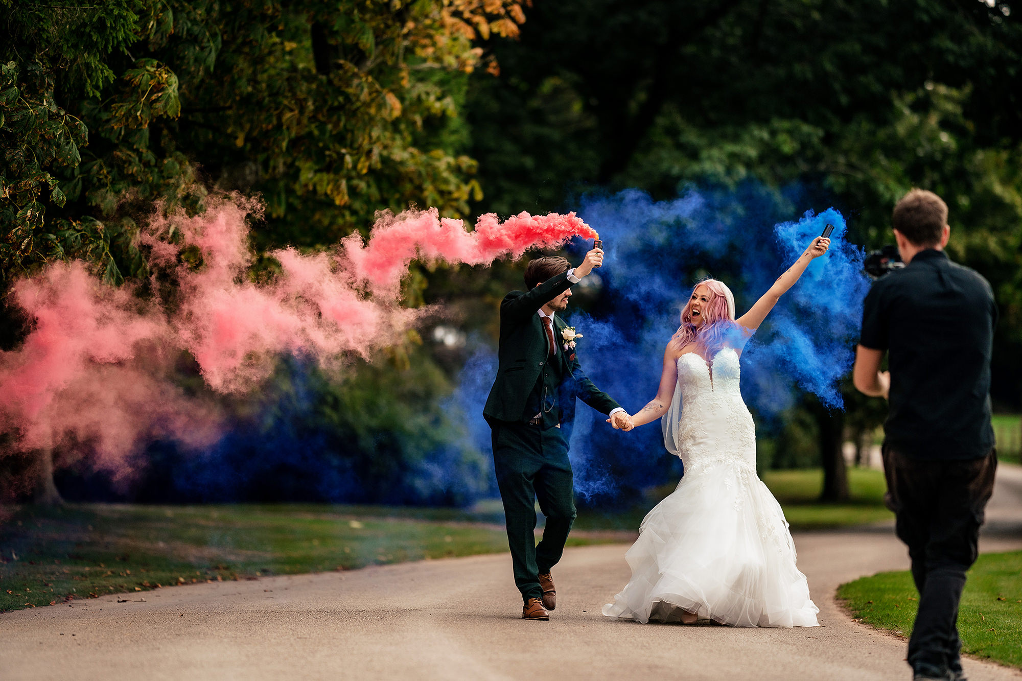 Bride and groom running with pink and blue smoke flares at their Standon Hall wedding
