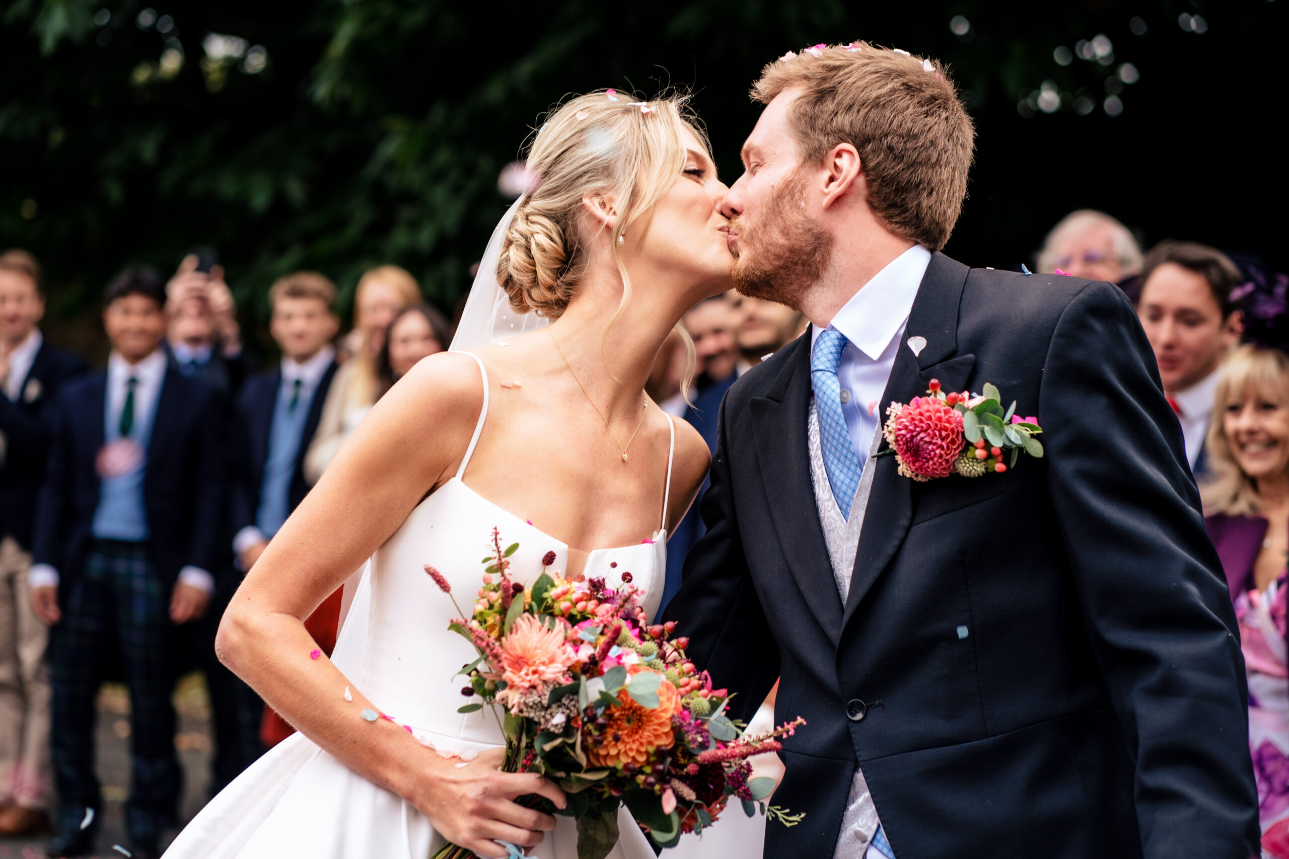 Bride and groom kissing in a cloud of petal confetti, Cheshire wedding photographer
