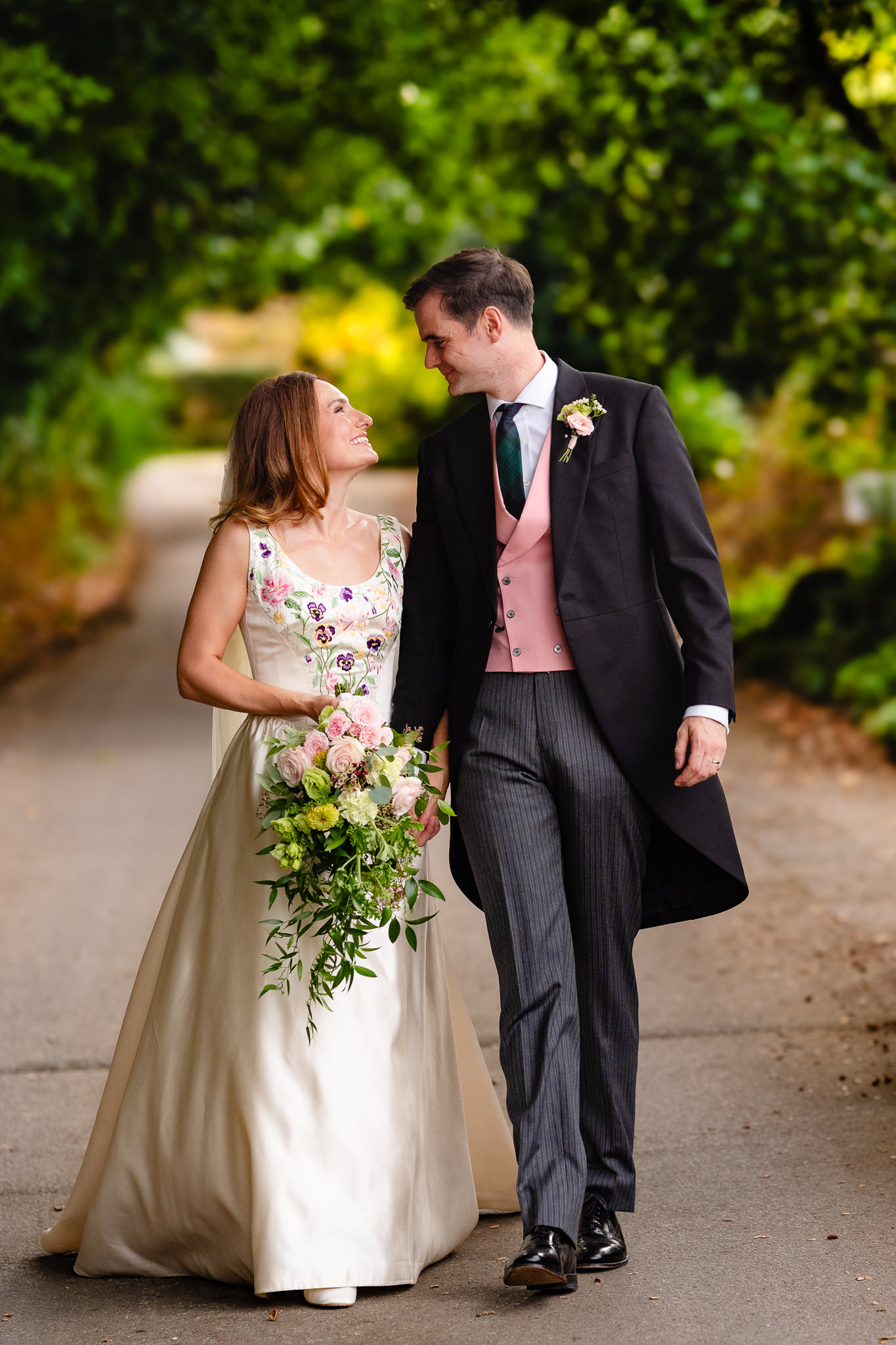 Bride and groom walking together down a leafy country lane
