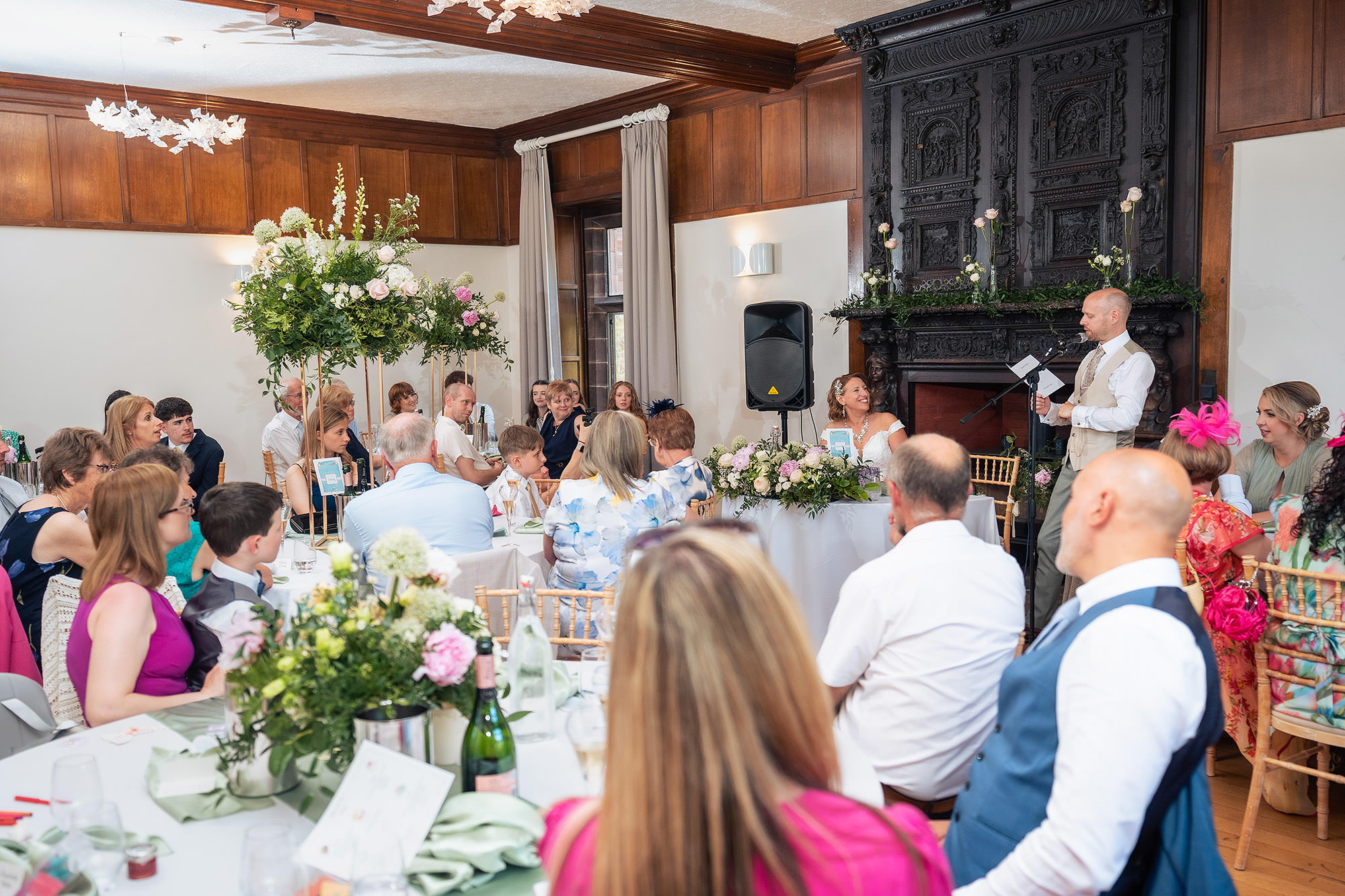 Wide view of guests seated in the reception room at Salt House listening to the wedding speeches