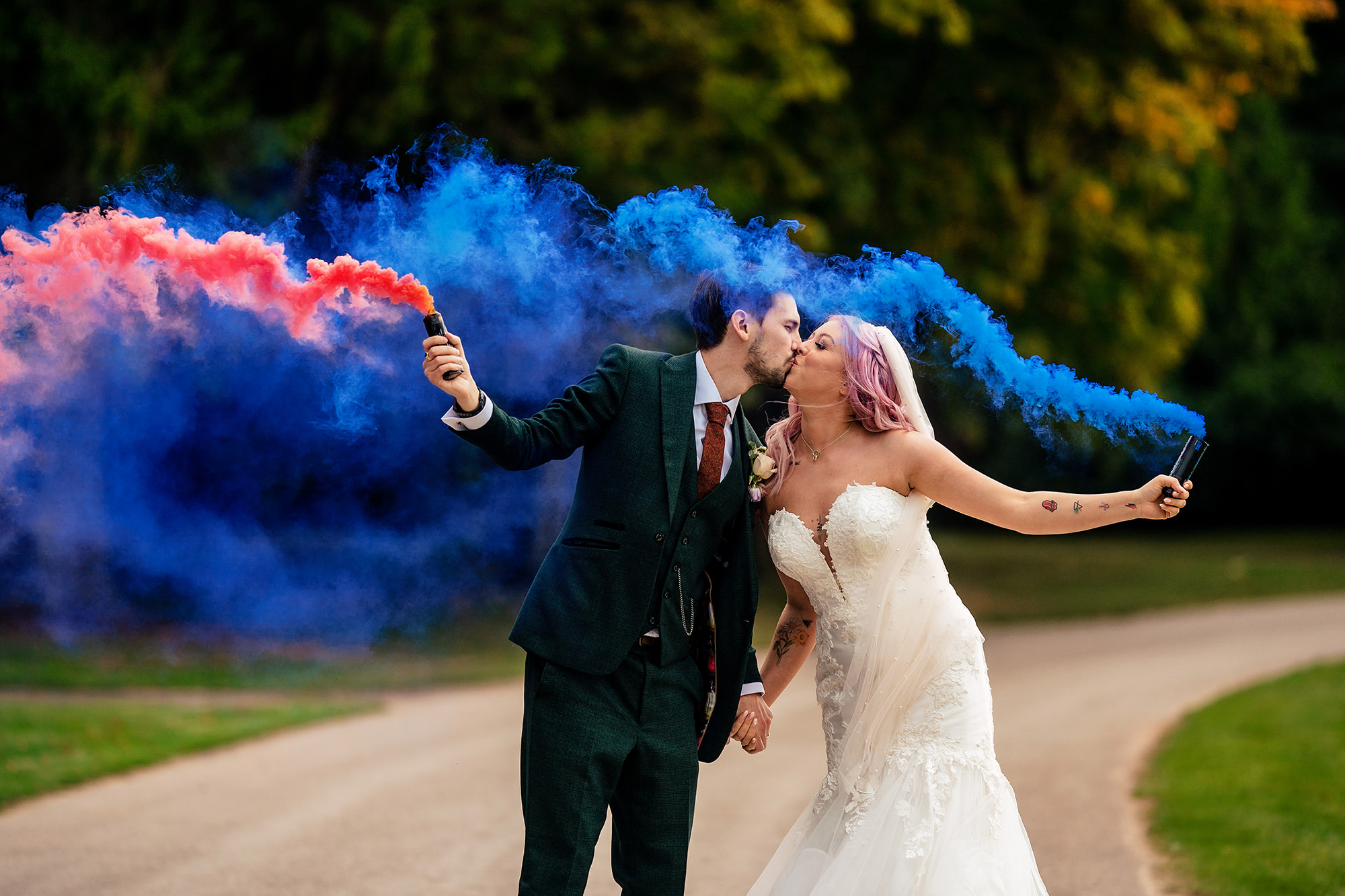 Bride and groom kissing surrounded by pink and blue smoke, Standon Hall wedding photographer