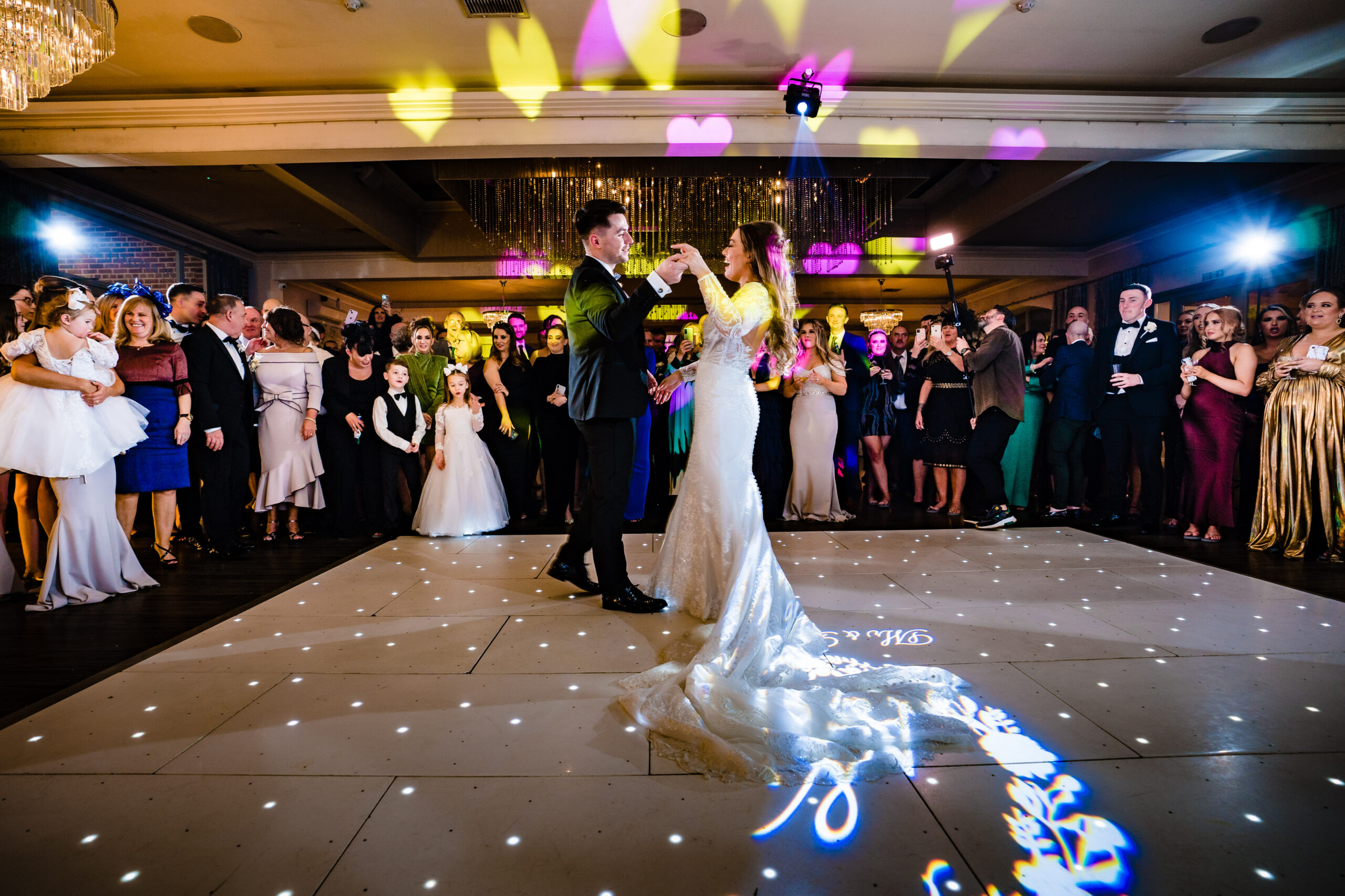 Wide view of Abbie and Jamie’s first dance under heart shaped lights at Merrydale Manor
