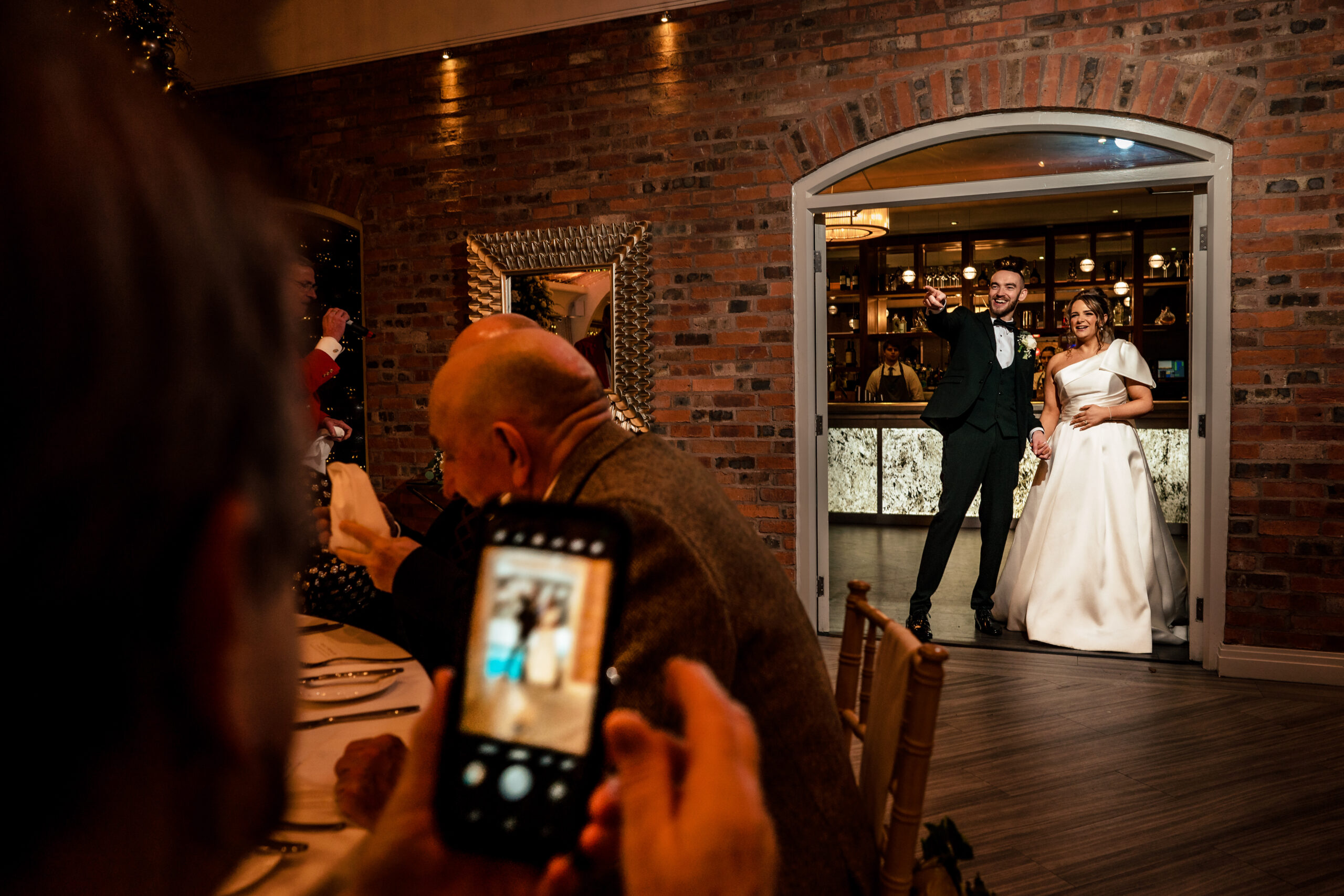 A guest capturing their own photo of the newlyweds in the doorway at Colshaw Hall