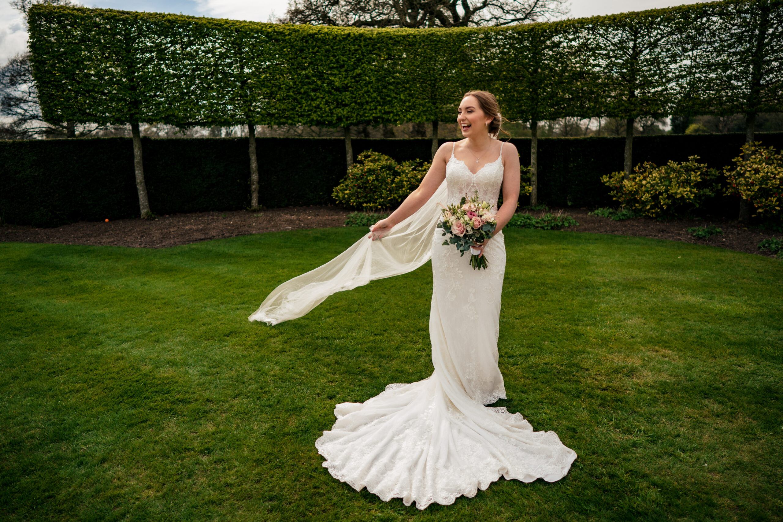 Bethany swishing her veil on the lawn in the hedge garden at Merrydale Manor