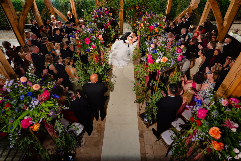 View from above of Kim and Glynn walking back down the flower lined aisle to cheering guests, Nottingham wedding photographer