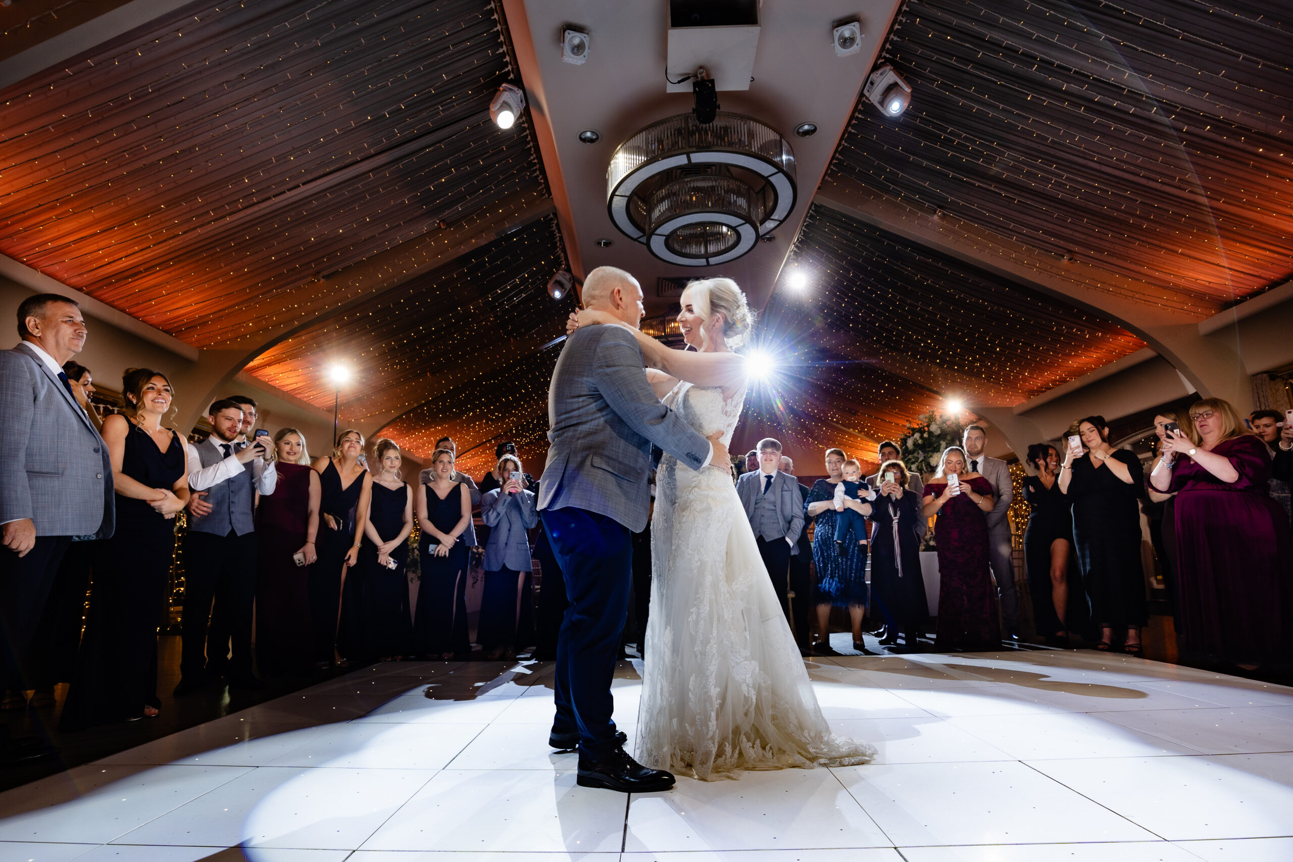 Bride and groom during their first dance on the white dancefloor with every guest gathered around them, Colshaw Hall Cheshire wedding photographer