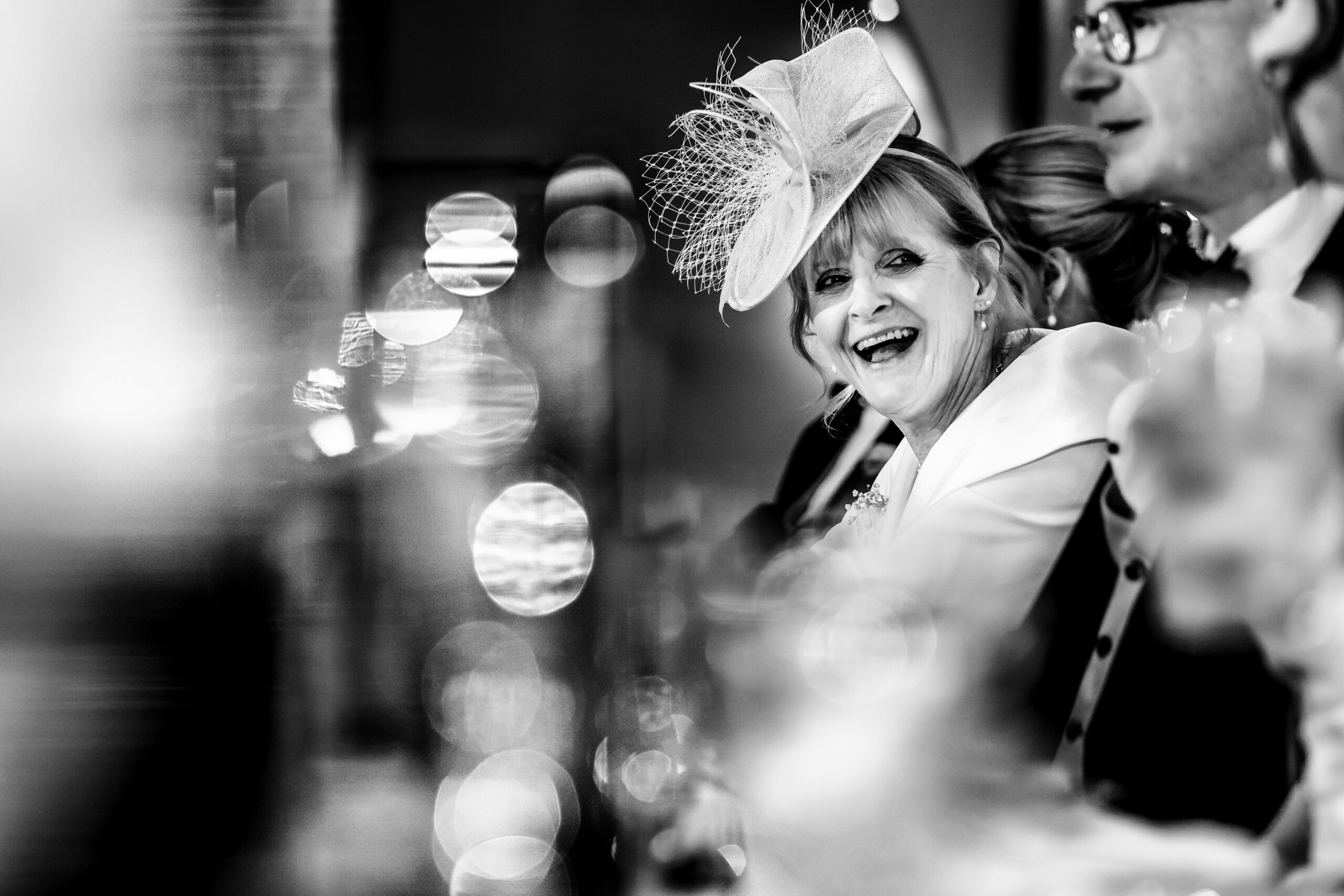 A guest laughing during the drinks reception, fairy lights glowing behind them
