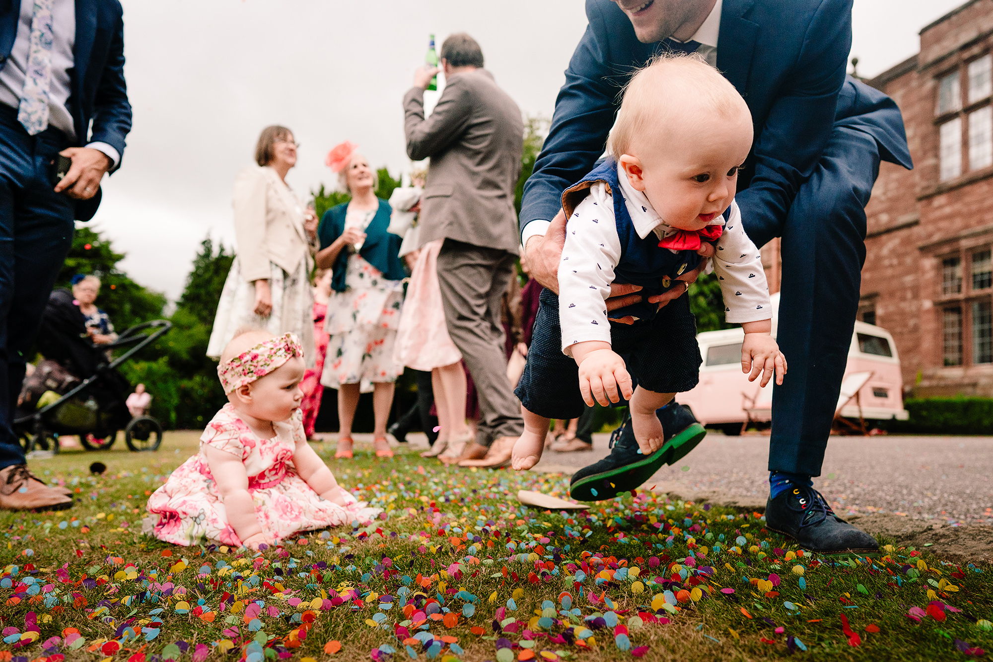 The flower girl playing in a huge pile of confetti on the lawn at Wrenbury Hall