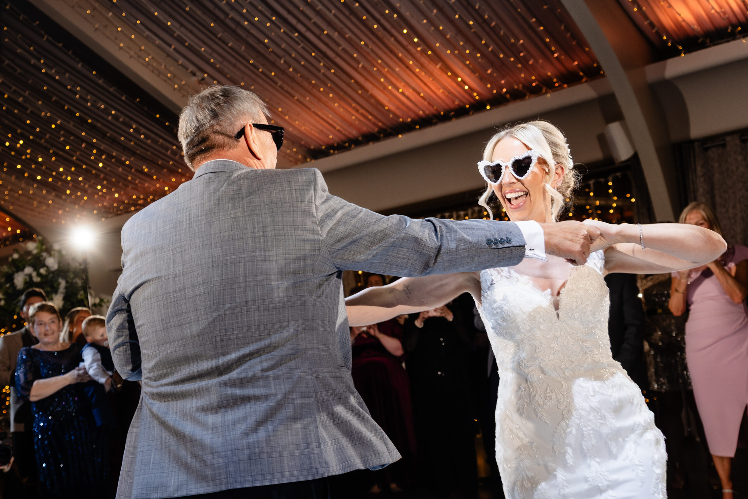 The bride and her dad dancing in matching heart shaped sunglasses, both laughing, Colshaw Hall wedding