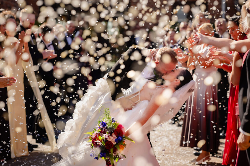 Kim and Glynn kissing in a thick cloud of confetti, Swancar Farm wedding photographer