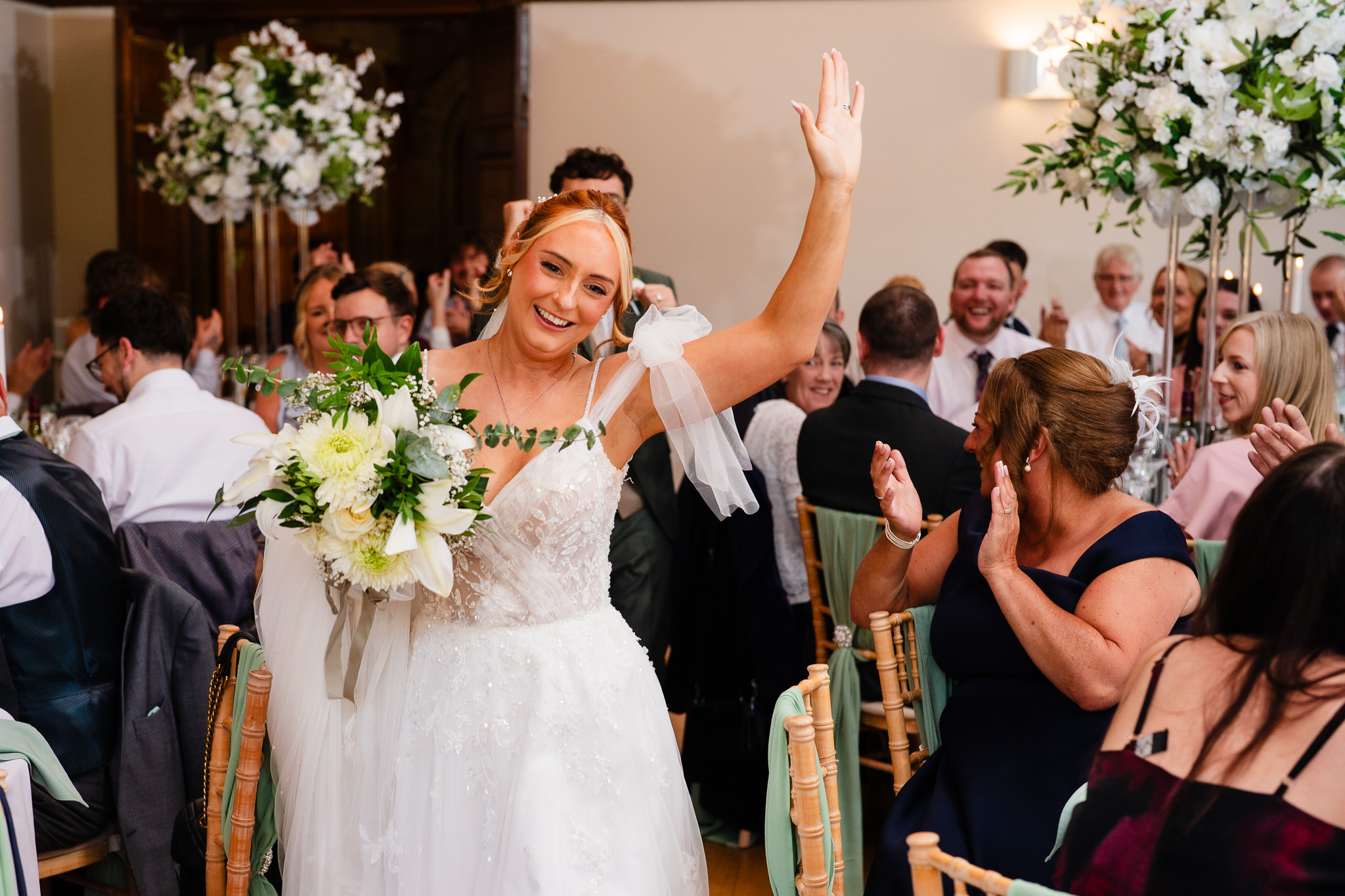 The bride’s grand entrance into the wedding breakfast, arm raised to cheering guests