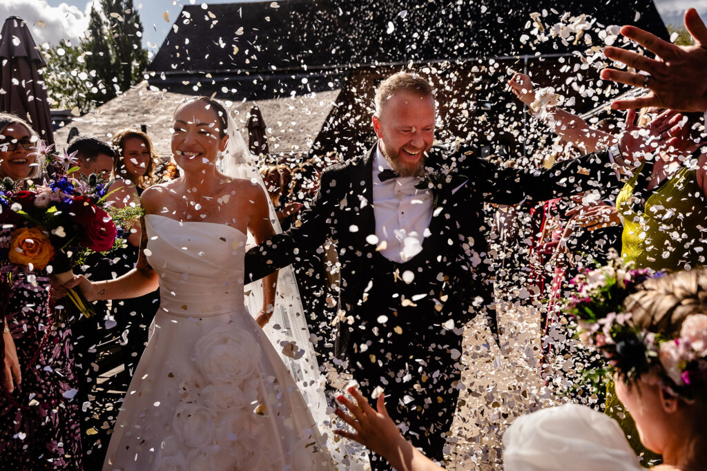 Kim and Glynn laughing as confetti rains down outside, Nottingham wedding photographer