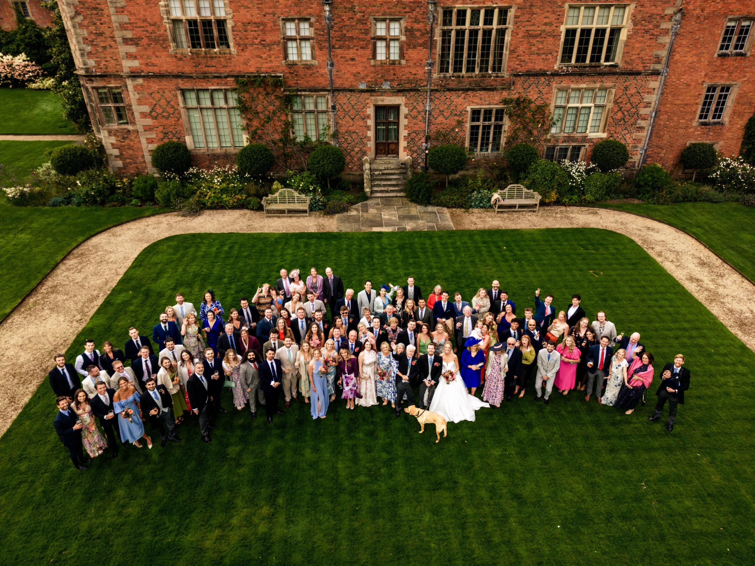 Aerial group photograph of all the wedding guests on the lawn in front of Dorfold Hall