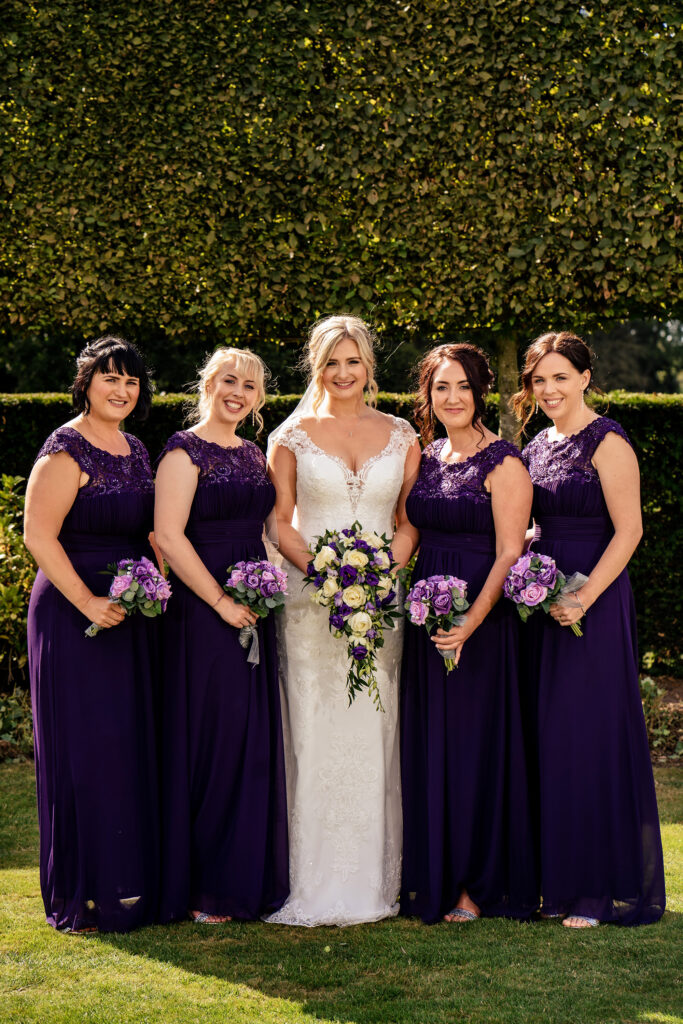 Bride with her bridesmaids in purple dresses holding purple bouquets, Cheshire wedding photographer