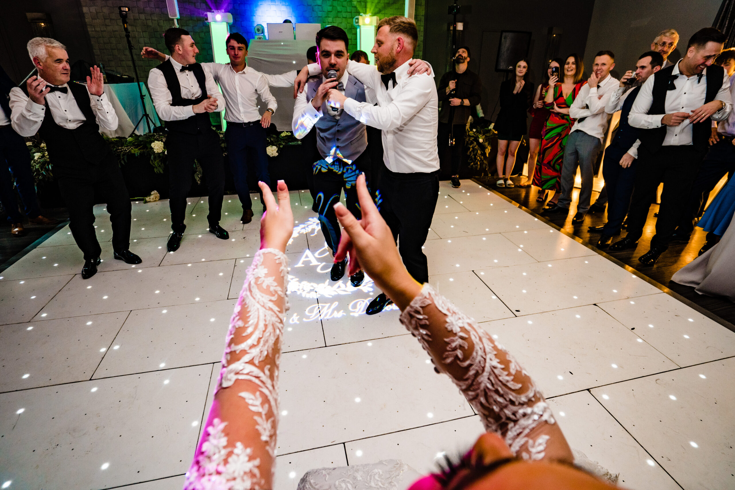 Abbie’s lace sleeves in the air as she cheers the lads dancing in front of her, Cheshire wedding photographer