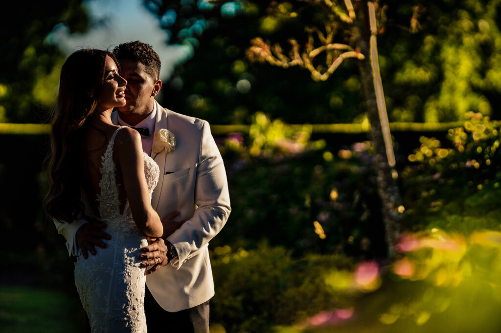 Gemma and Tyrone embracing in warm evening light in the gardens at Merrydale Manor, Cheshire wedding photographer