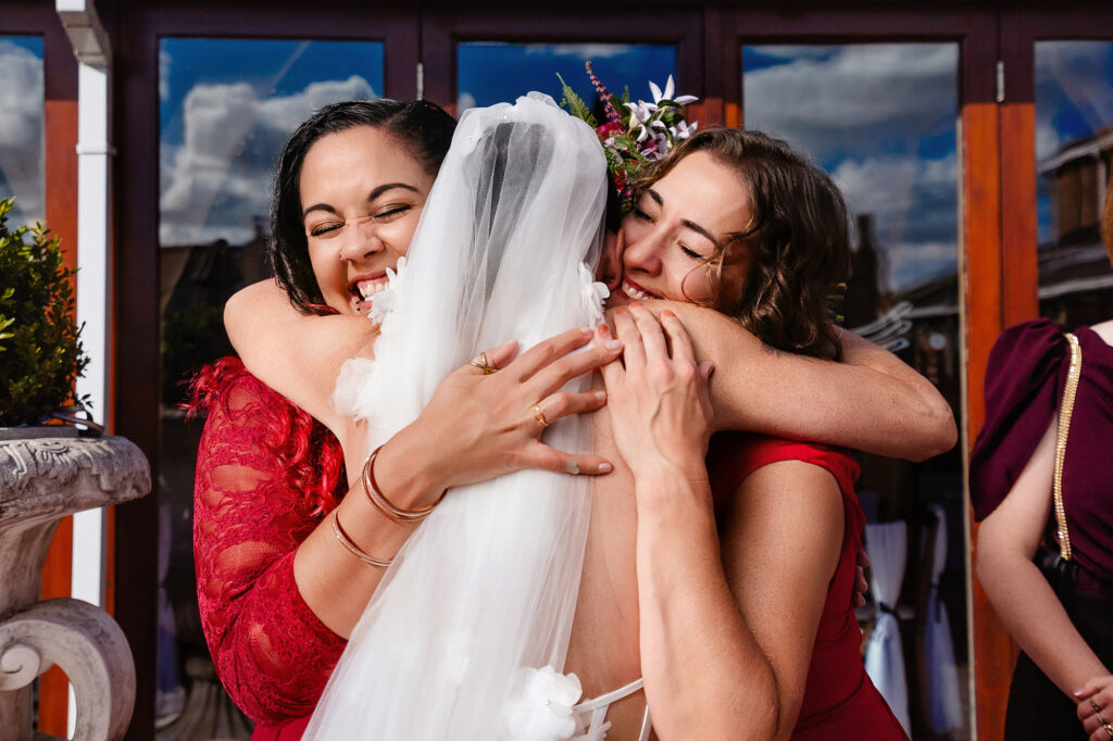 Kim hugged tightly by two guests in red after the ceremony, Swancar Farm wedding photographer