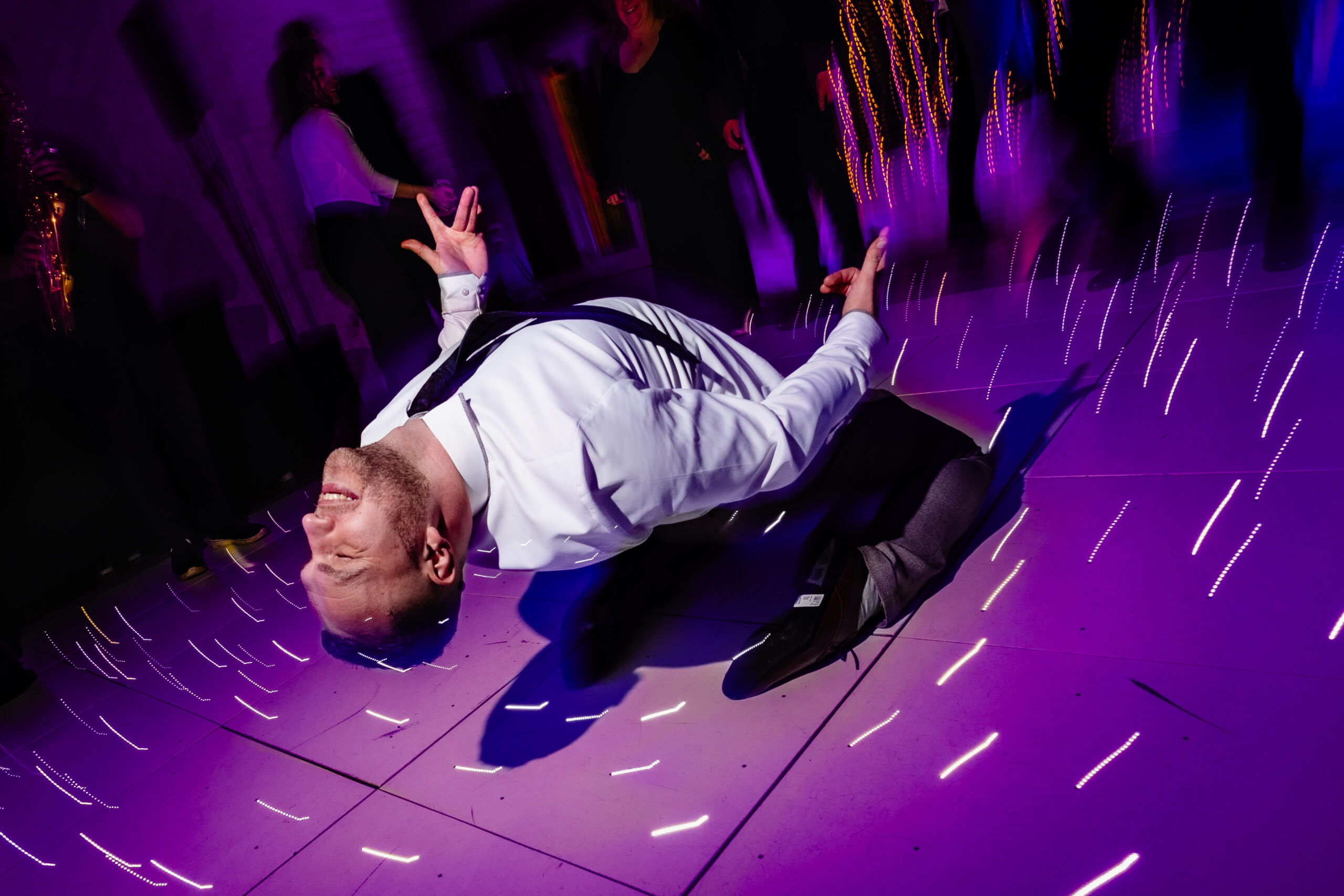 A guest flat on his back on the dancefloor mid dance move, grinning, Colshaw Hall Cheshire wedding photographer