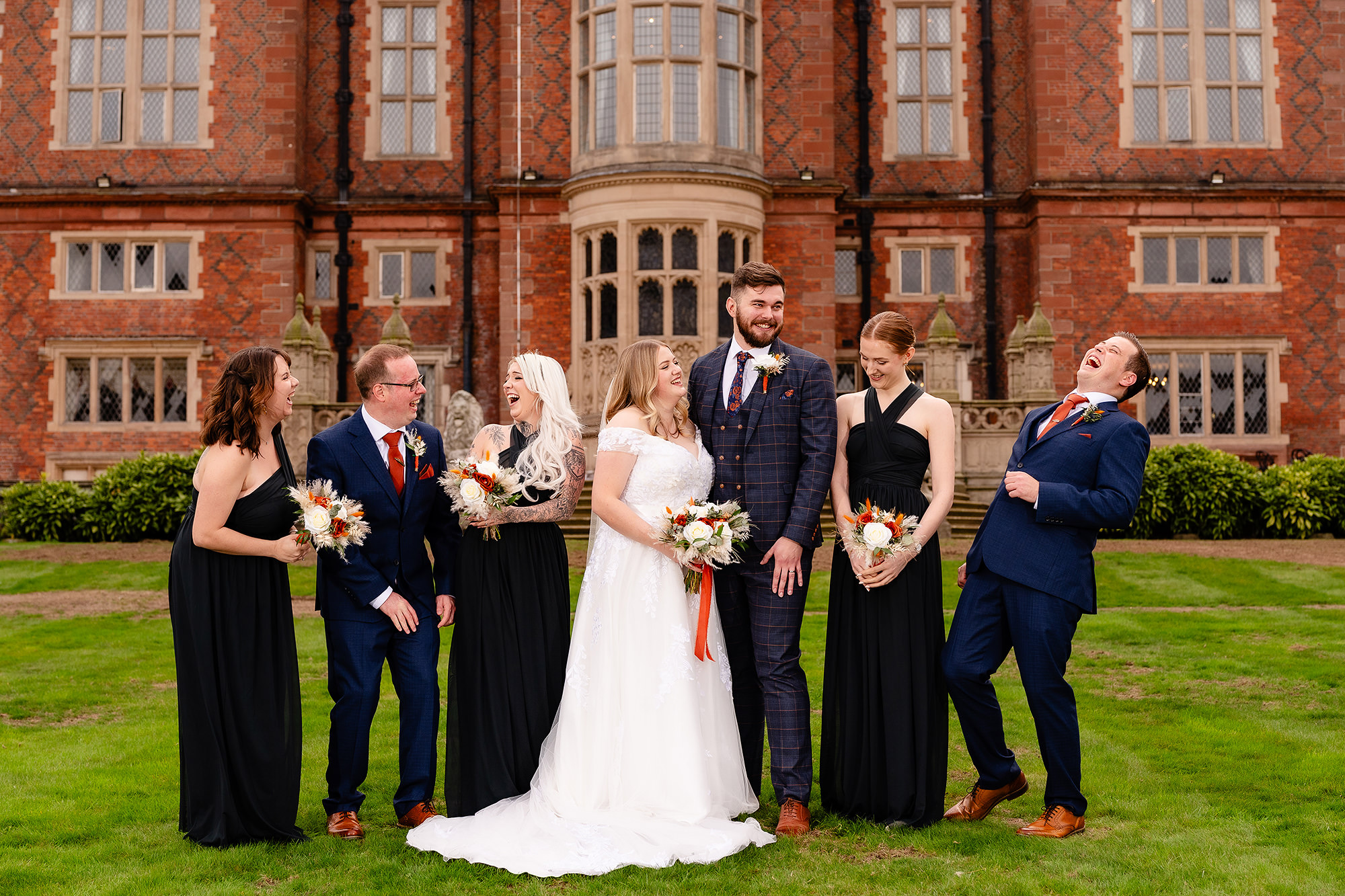 Annie and Tom laughing with their wedding party at Crewe Hall, Cheshire wedding photographer