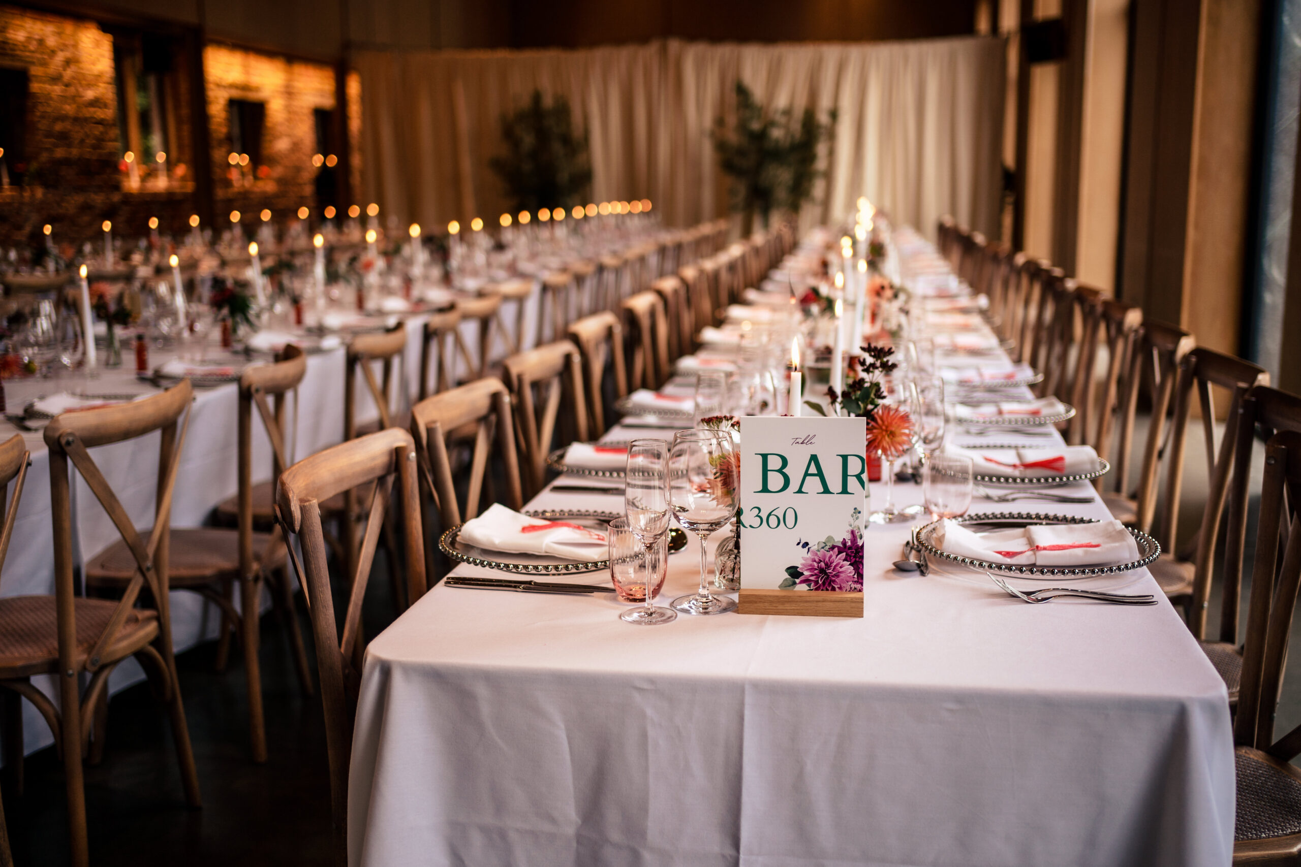 Long tables set with candles and dahlias for the wedding breakfast at L’Ecurie, Dorfold Hall
