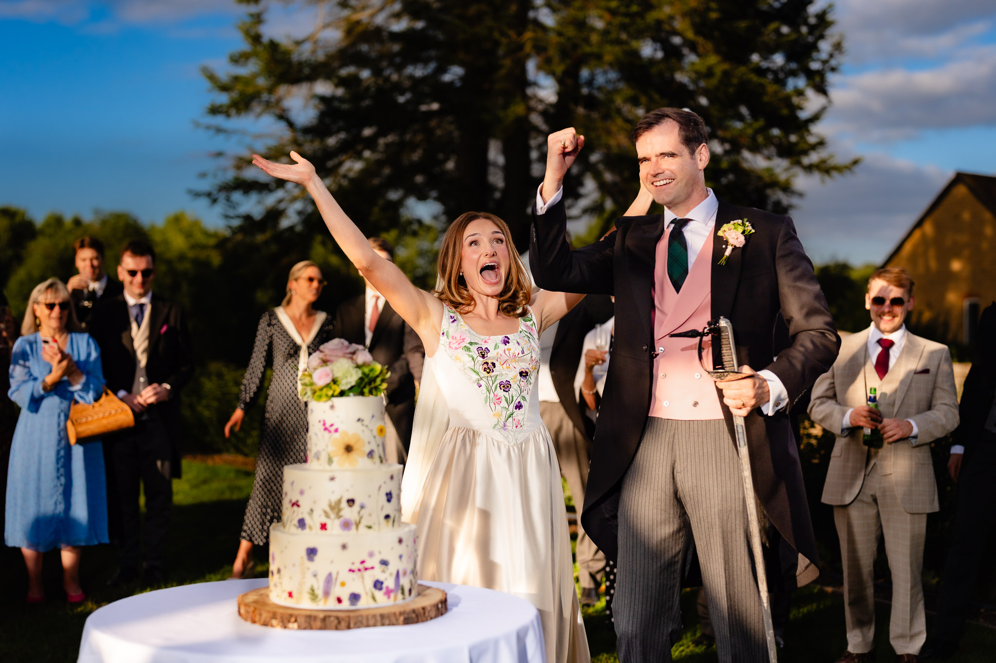 Bride throwing her arms in the air in celebration straight after cutting the cake