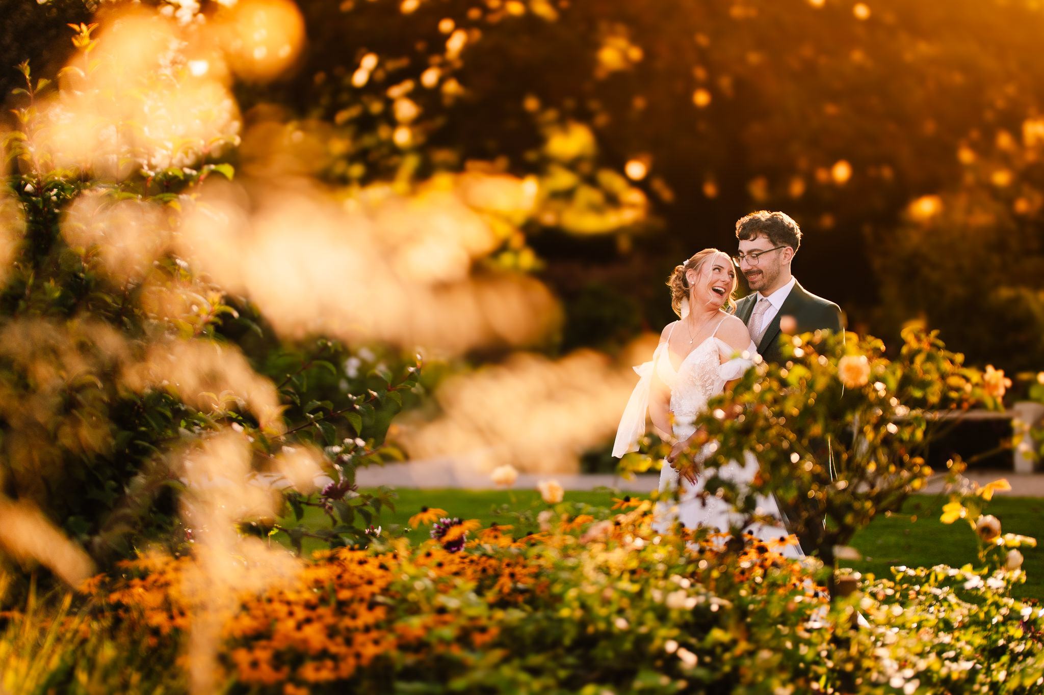 Bride and groom sharing a golden hour portrait among tall flowers at Salt House