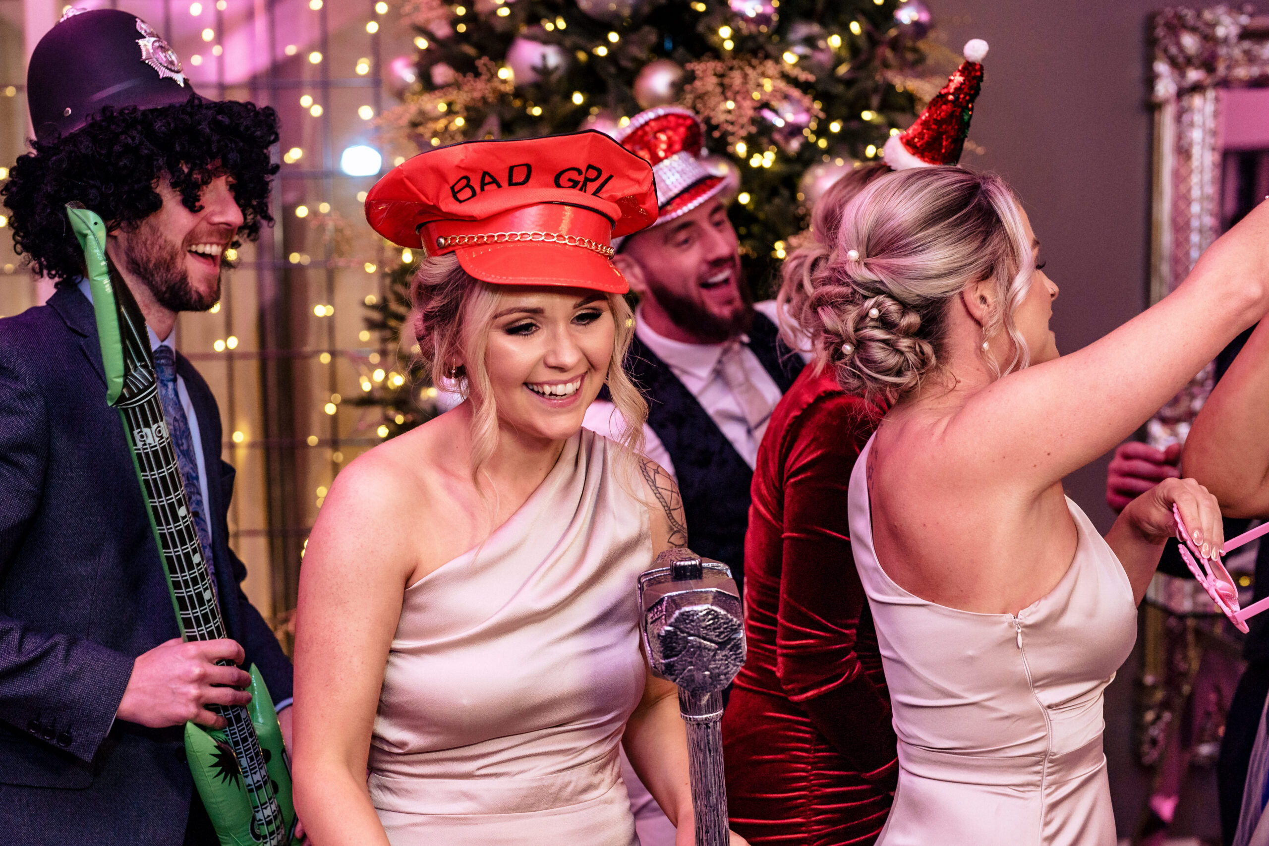 The bridal party having fun with props by the Christmas tree