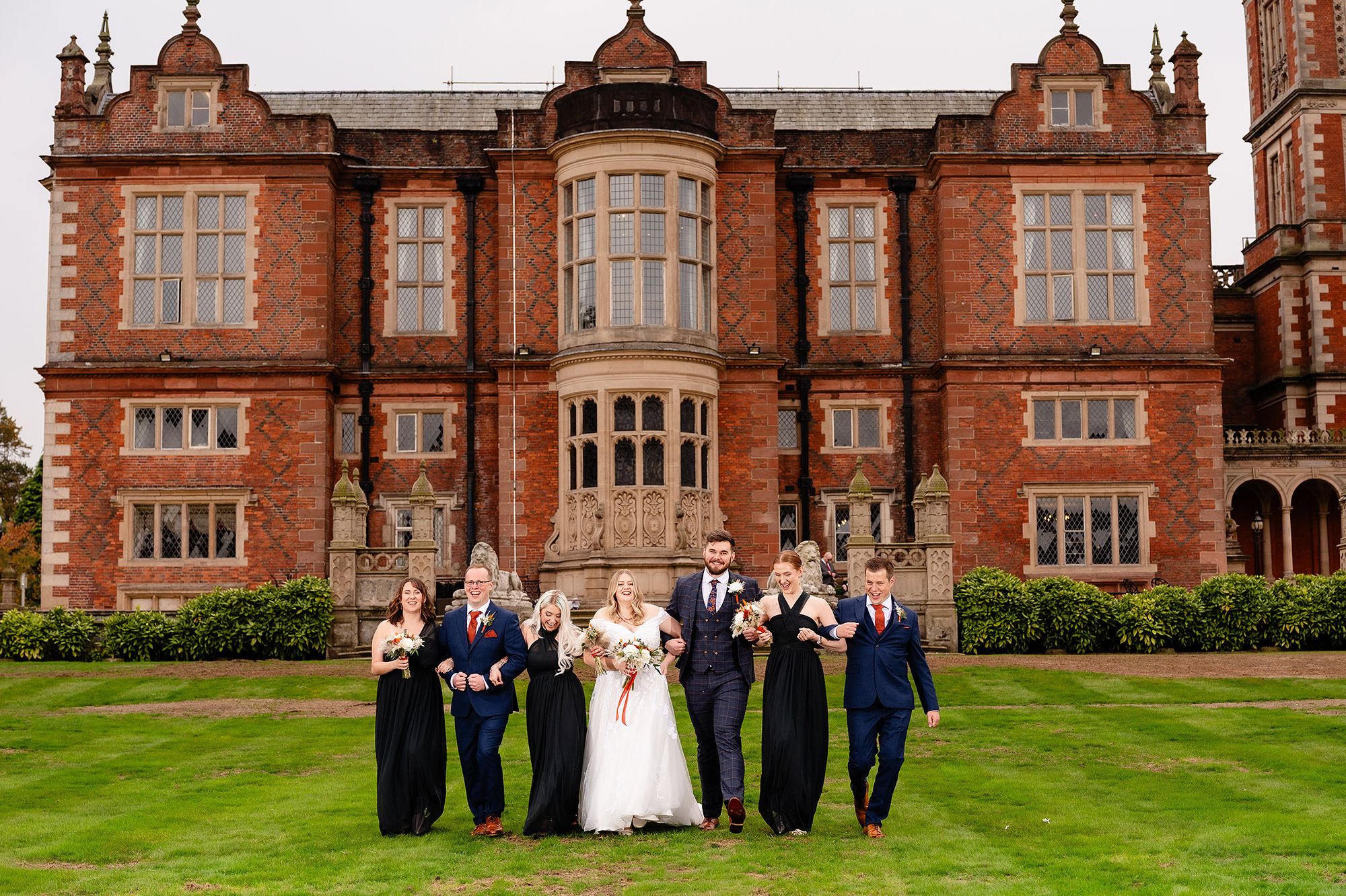 The wedding party walking together across the lawn at Crewe Hall, Cheshire wedding photographer