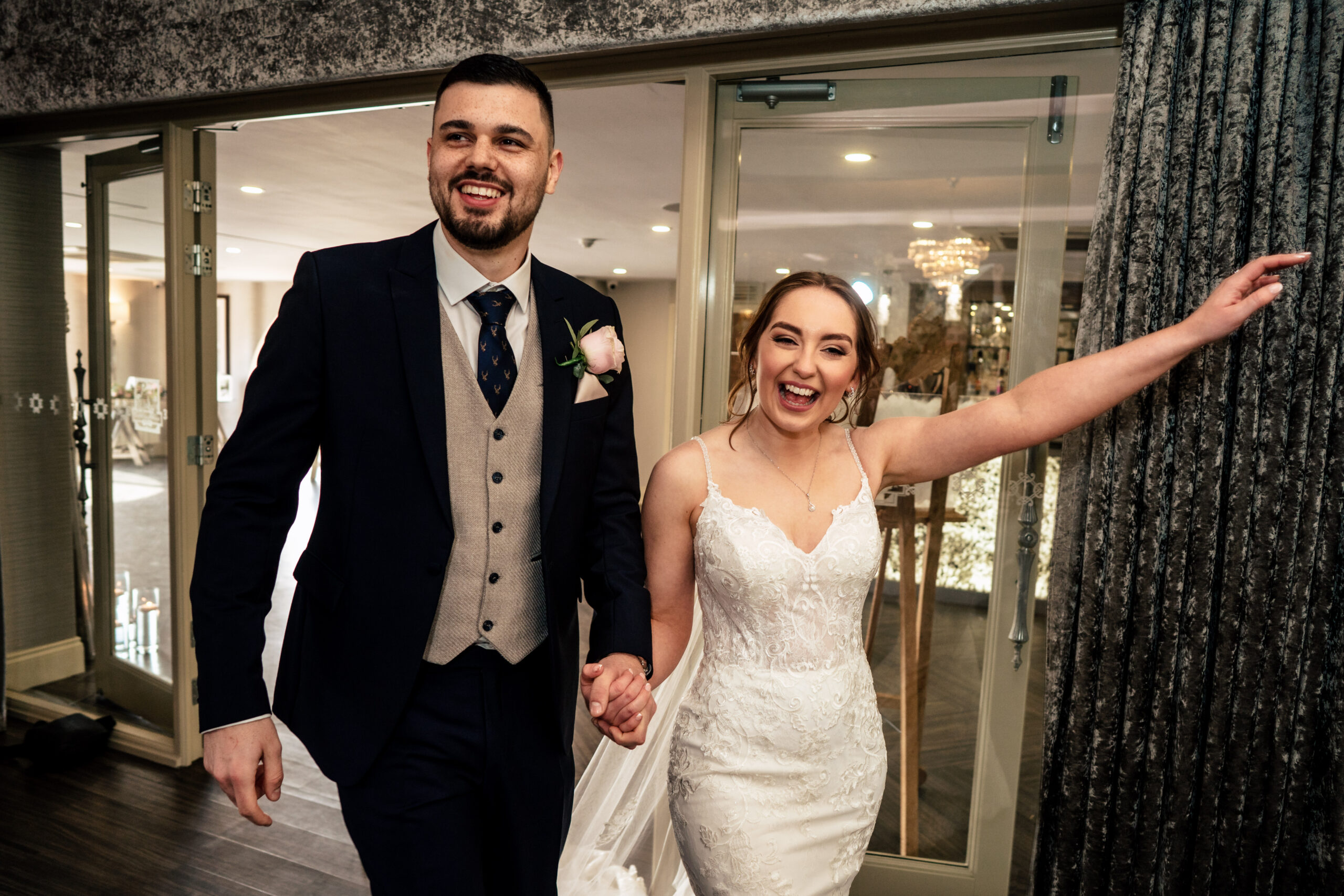 Dean and Bethany making their grand entrance into the reception room, Bethany's arm flung out