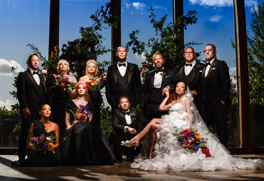 Dramatic flash lit composite of the bridal party, bridesmaids in black, groomsmen in black tie, Kim seated in front of the glass barn, Swancar Farm wedding photographer