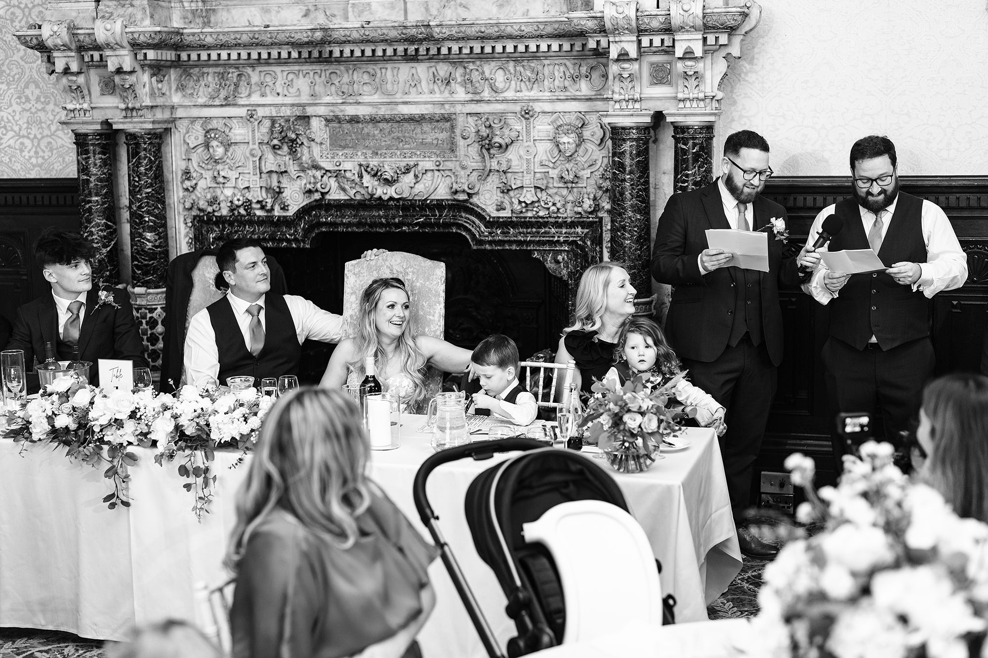 Black and white photograph of the top table in front of the carved stone fireplace at Crewe Hall during the speeches