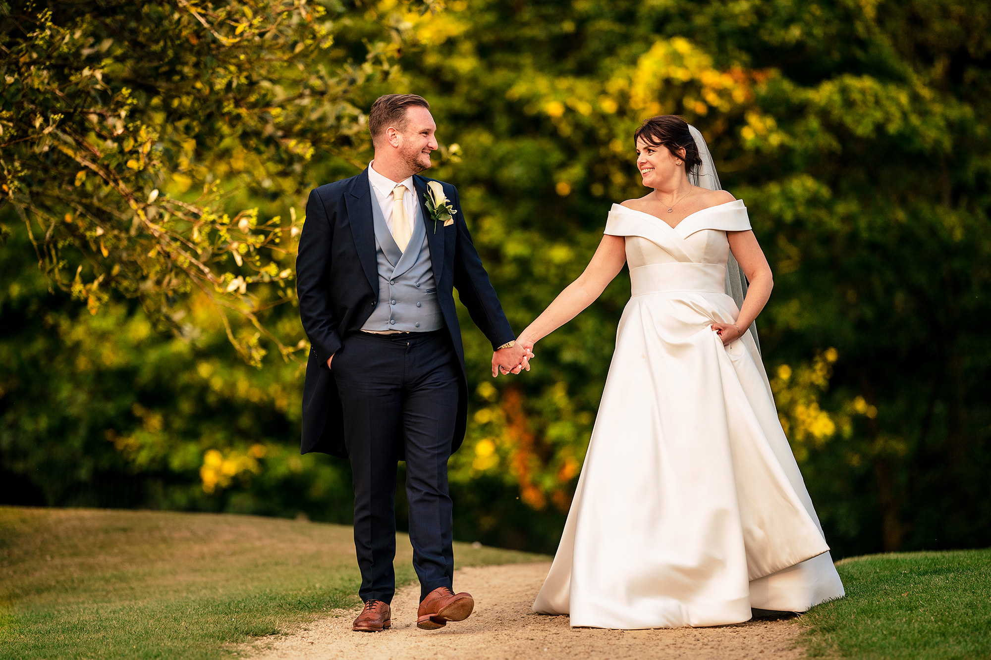 Laura and Ryan walking together hand in hand in the golden evening light, Merrydale Manor wedding photographer