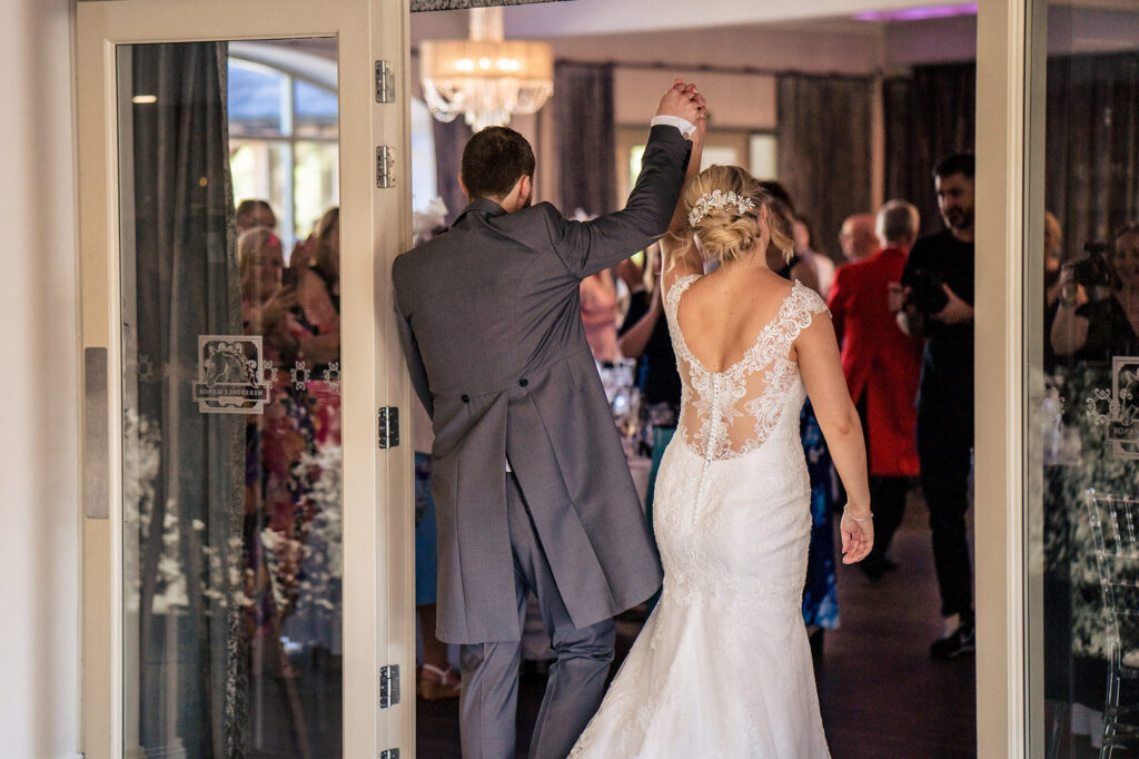 Groom raising his arm as the couple make their grand entrance into the reception, Cheshire wedding photographer