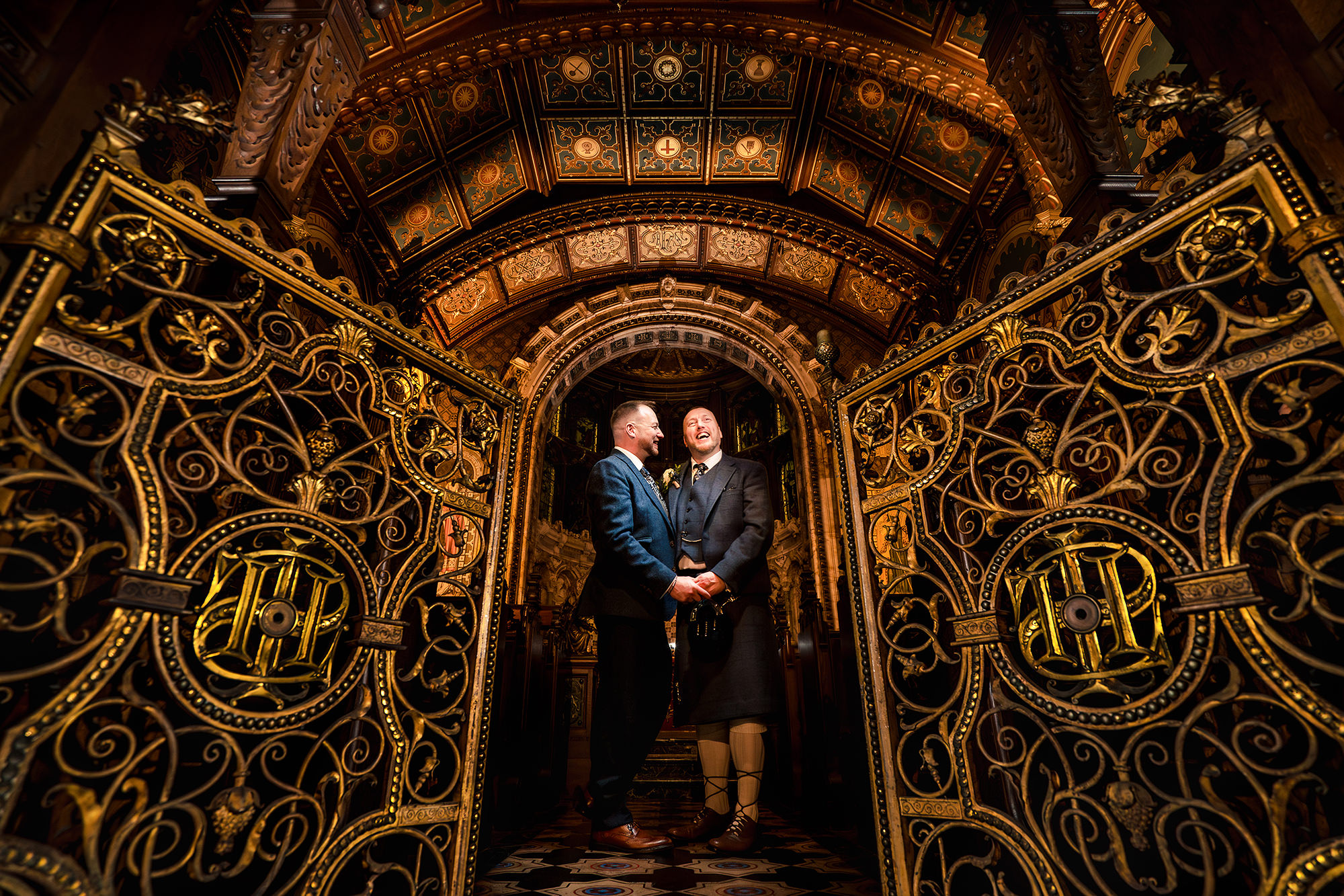John and Neill pictured together under the lit archway at the chapel, Crewe Hall, in the evening