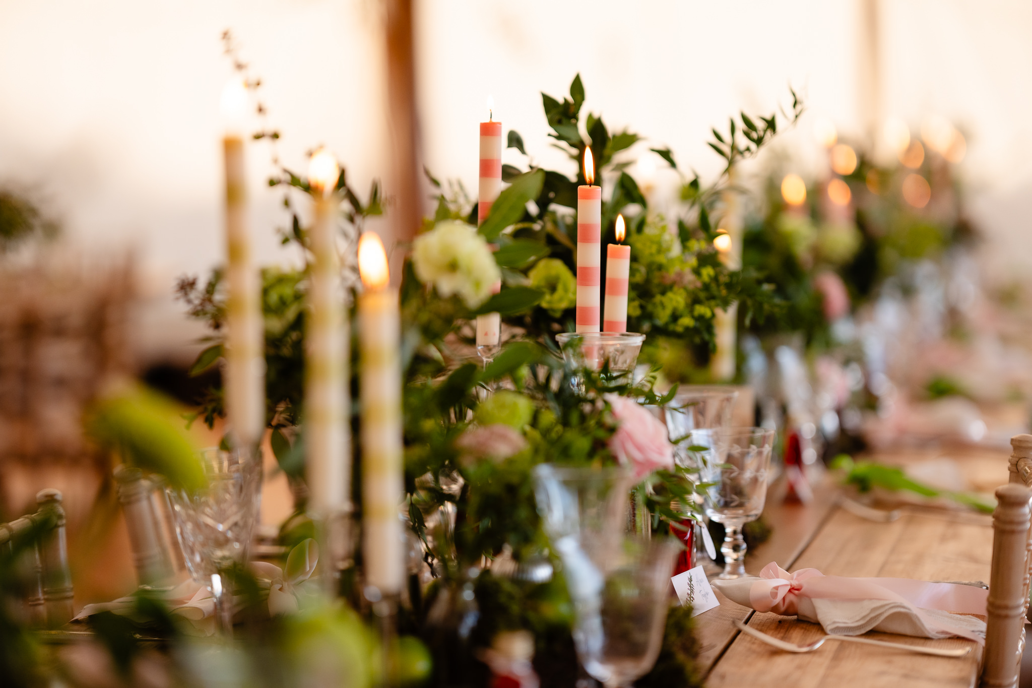 Candles, foliage and garden flowers running down the centre of the wedding table